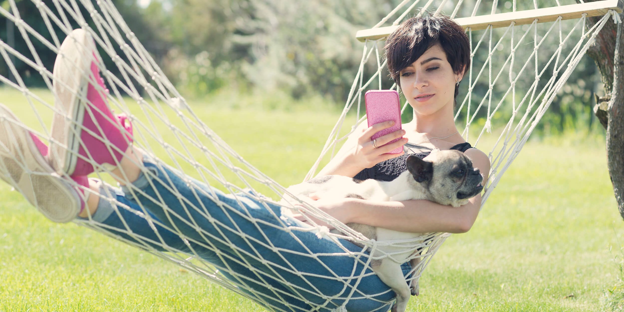 Young woman with her puppy dog lying on the hammock.