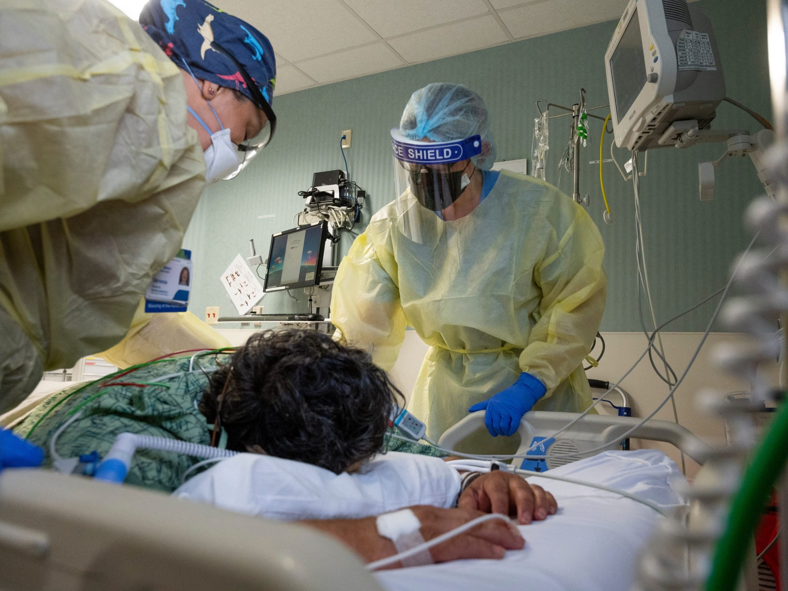 Nurses Assistant Vanessa Gutierrez, left, and Jamie McDonough, RN, talk to a COVID-19 patient in the COVID ICU at St. Joseph Hospital in Orange, CA on Wednesday, July 21, 2021.