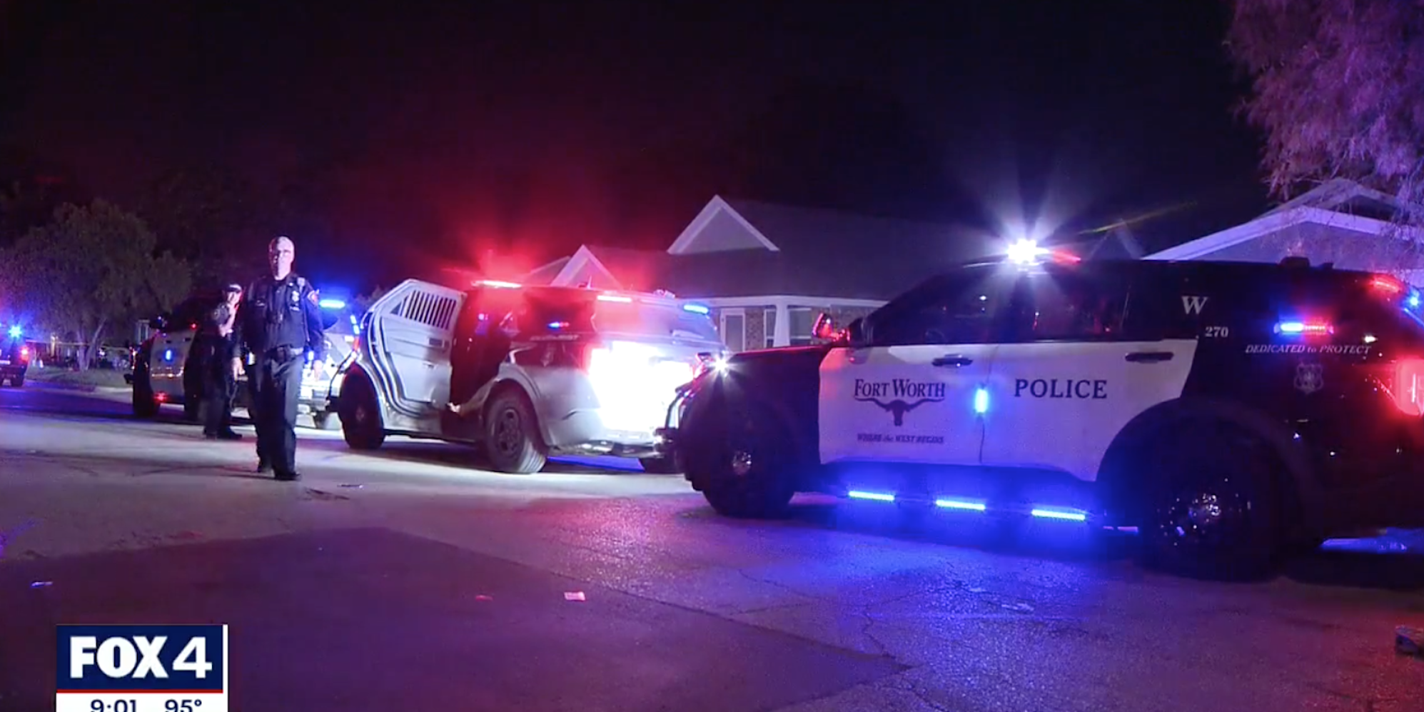 A police officer and Fort Worth police cars on a street at night