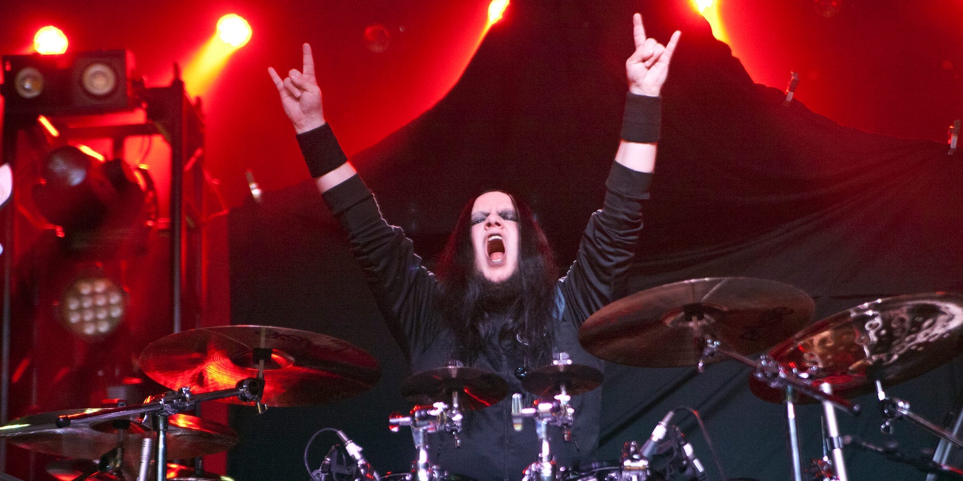 Joey Jordison raises his arms as he performs behind his drumkit