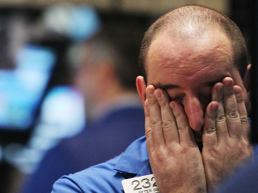 A trader rubs his eyes on the floor of the New York Stock Exchange.