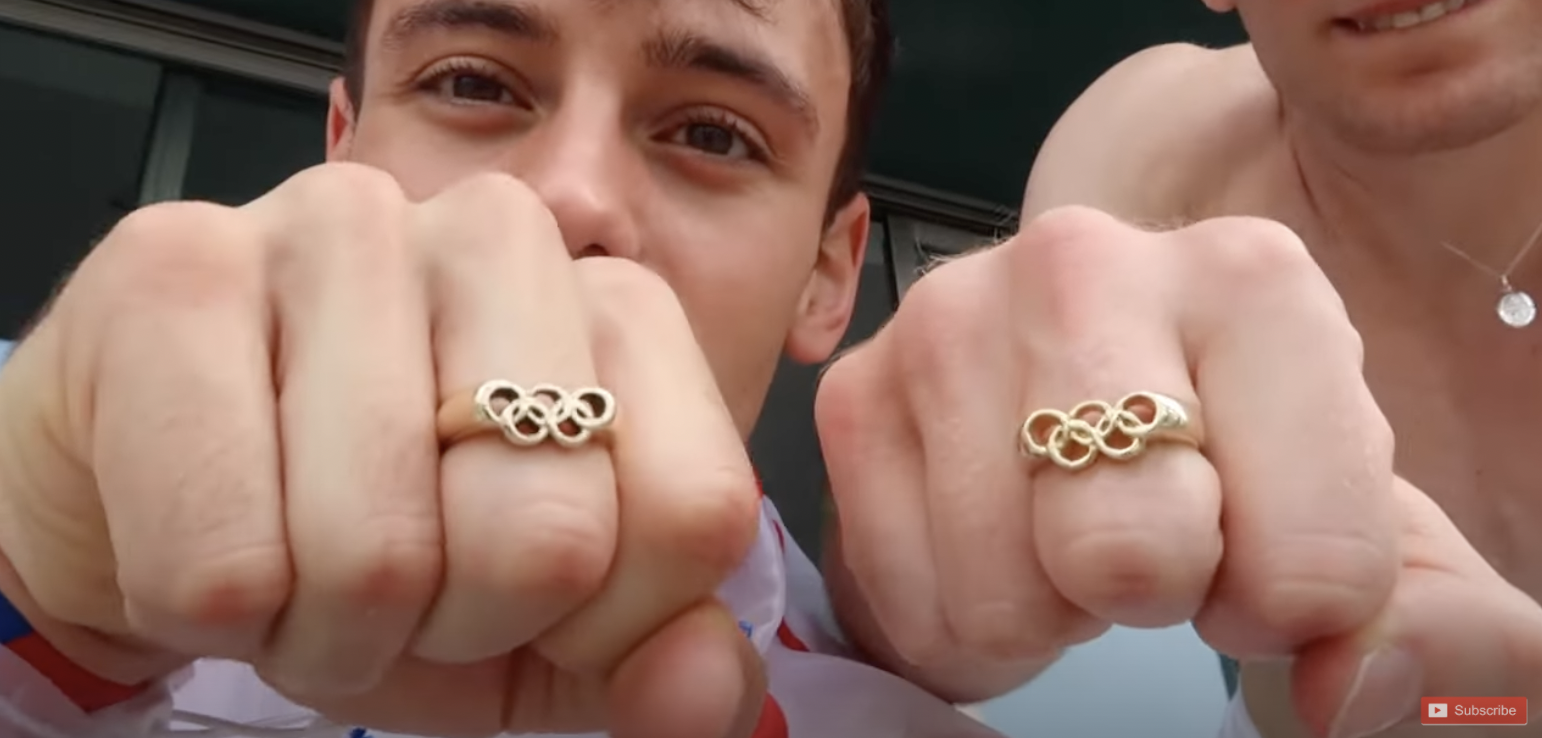 Tom Daley and Matty Lee show off their matching Olympic golden ring jewellery after they won gold medals in diving on Monday.