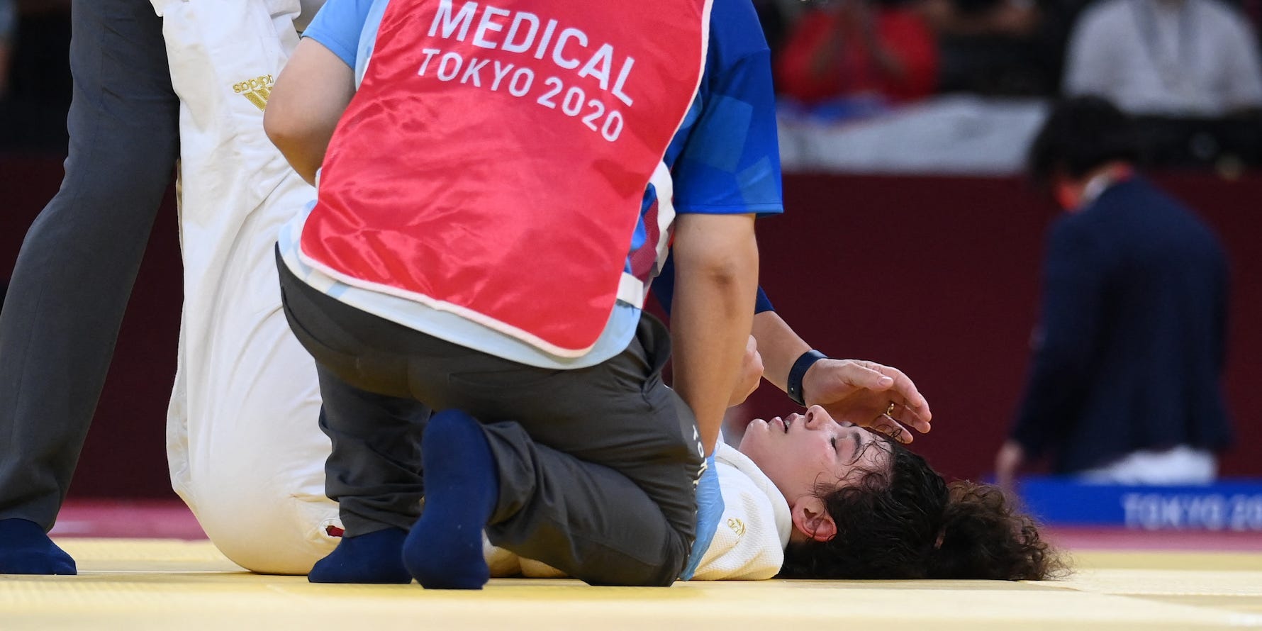 Madina Taimazova is attended to after passing out on the mat at the Tokyo Olympics.