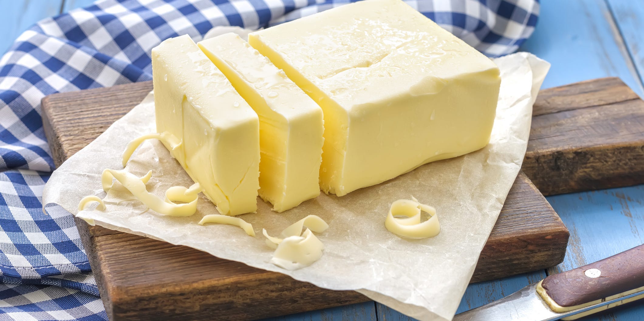 A block up butter cut up into segments with some butter curls surrounding it