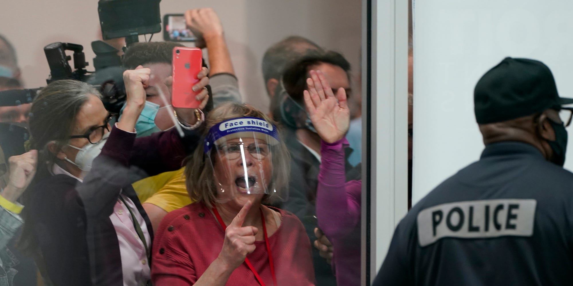 Surplus election challengers yell behind windows at the central counting board in Detroit, Michigan