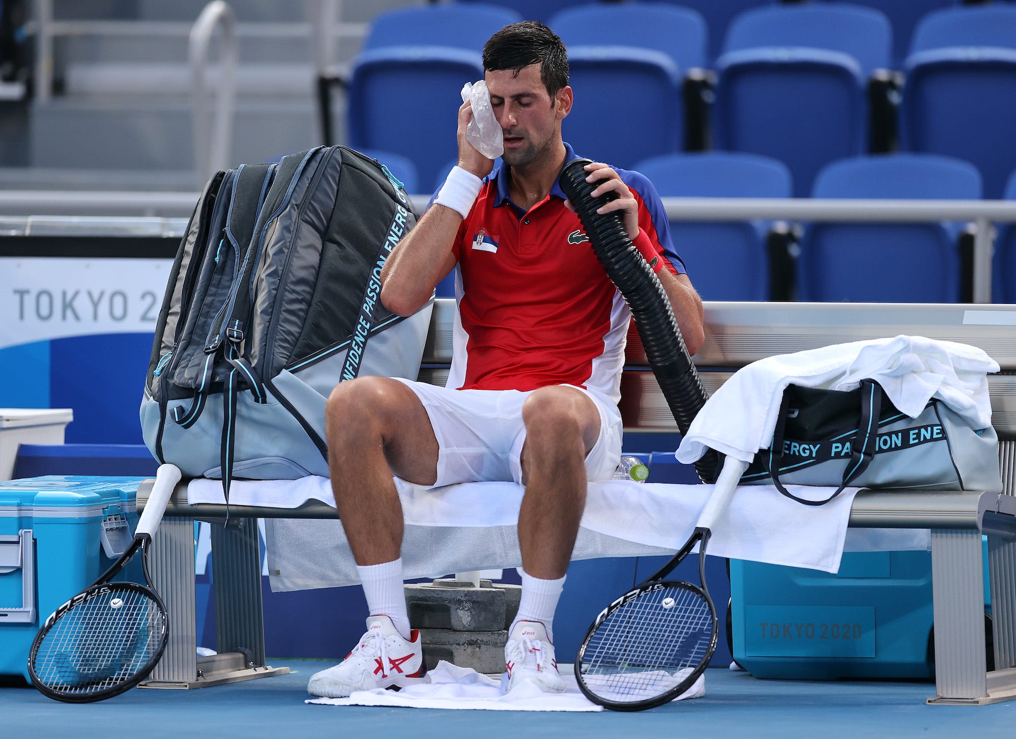 Novak Djokovic tries to keep cool under the heat at the Tokyo Games by using an ice pack and fan.