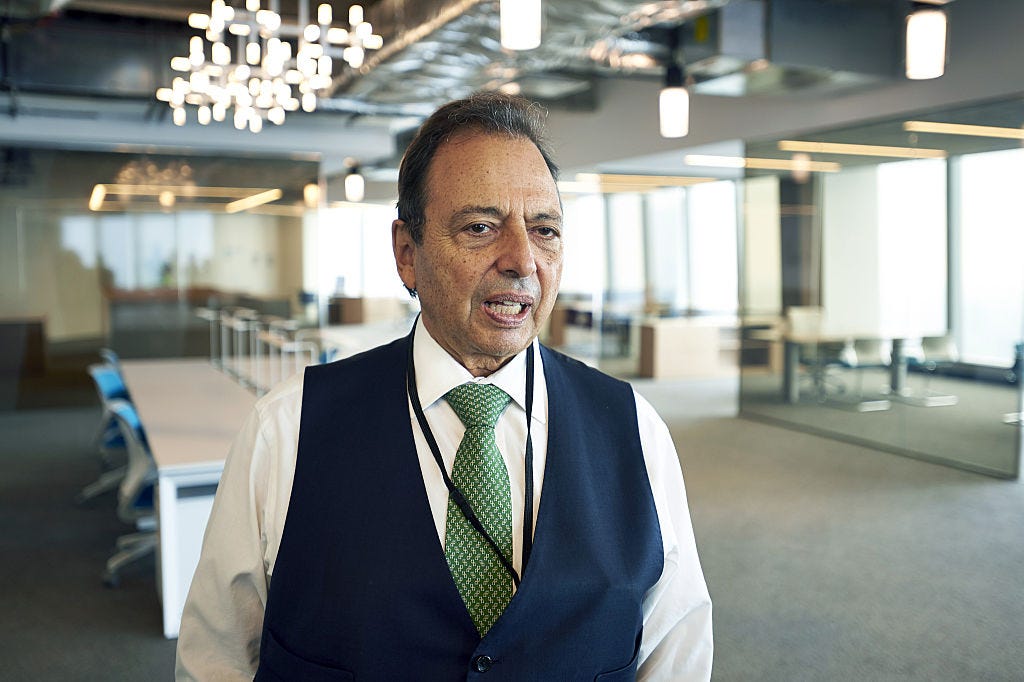 Douglas Durst, chairman of The Durst Organization, wears a white shirt and black waistcoat in a corporate meeting room.