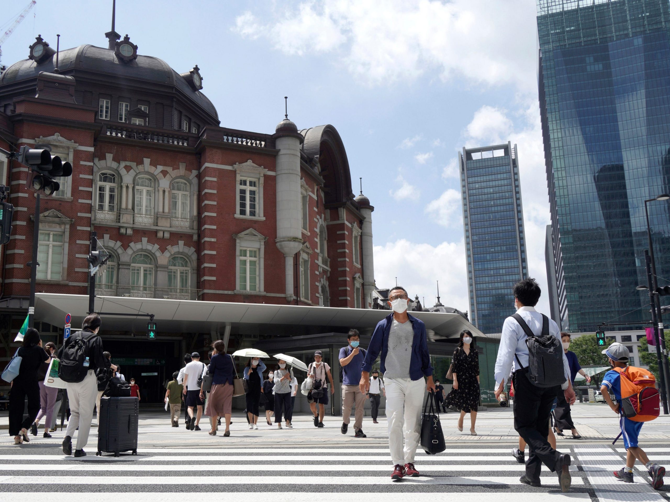 People walk across a crossing near Tokyo Station in Tokyo Thursday, July 29, 2021, a day after the record-high coronavirus cases were found in the Olympics host city