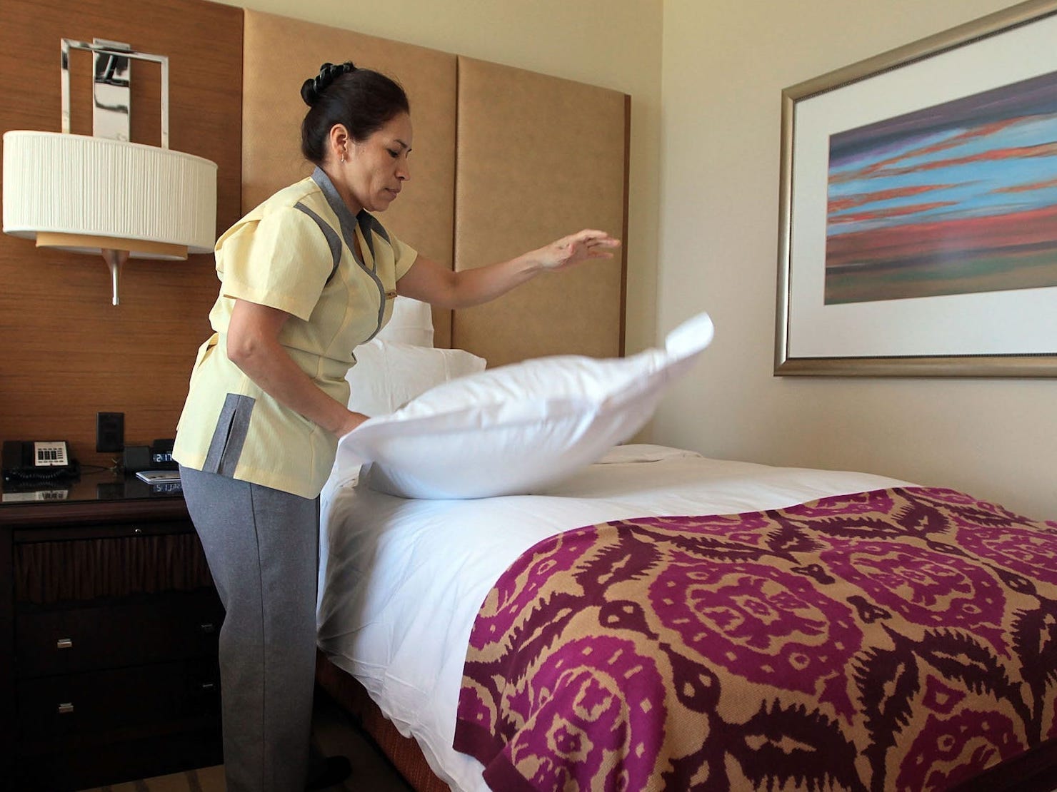 A hotel worker is making a bed.