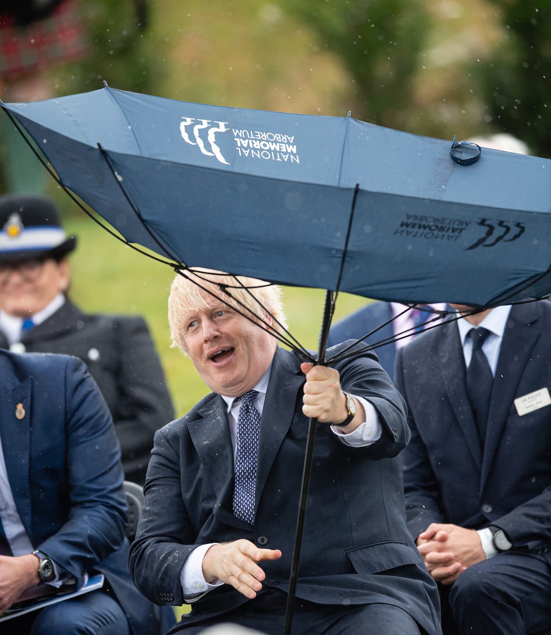 British Prime Minister Boris Johnson laughs as his umbrella is blown inside-out.