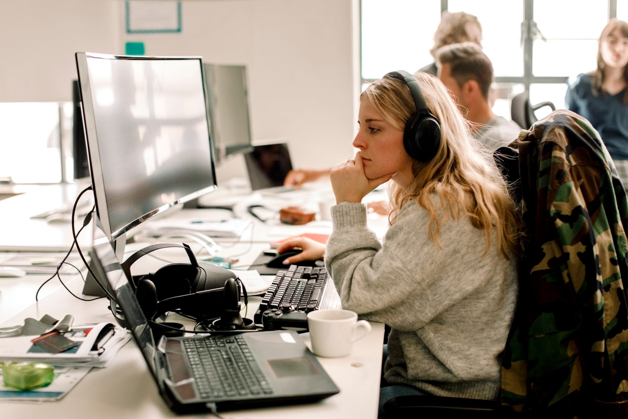 woman at office using desktop computer and laptop at desk