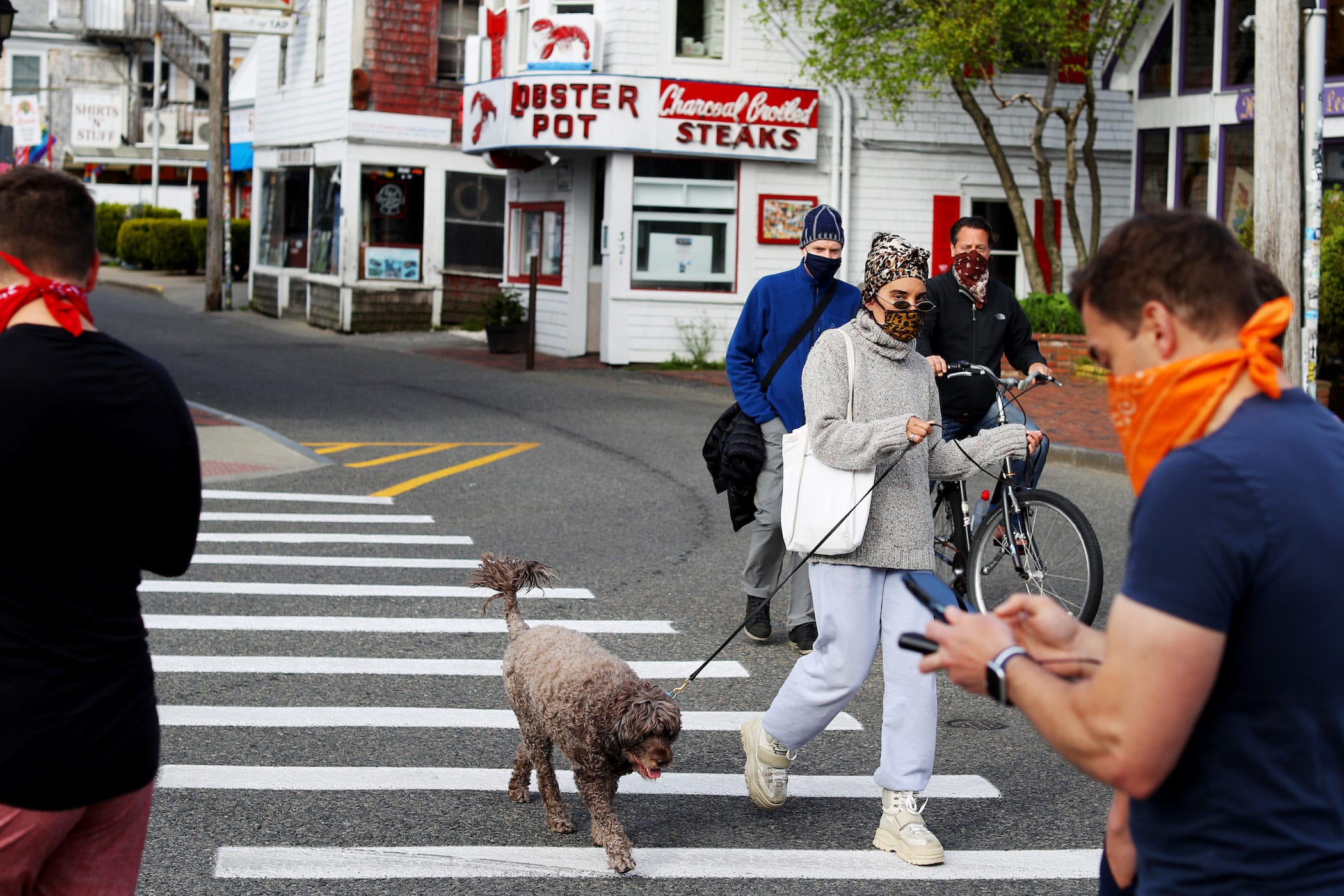 provincetown street with people walking, biking, dog walking, all wearing masks