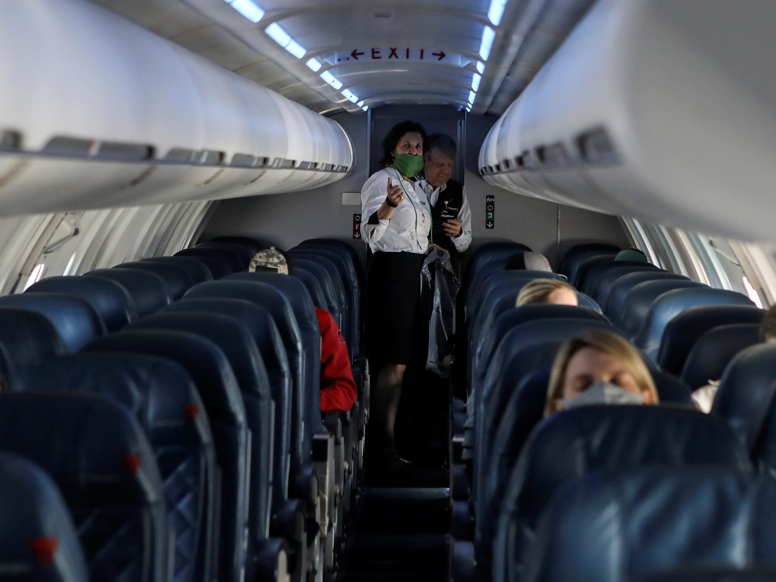 Two flight attendants talk in a nearly empty cabin on a Delta Airlines flight