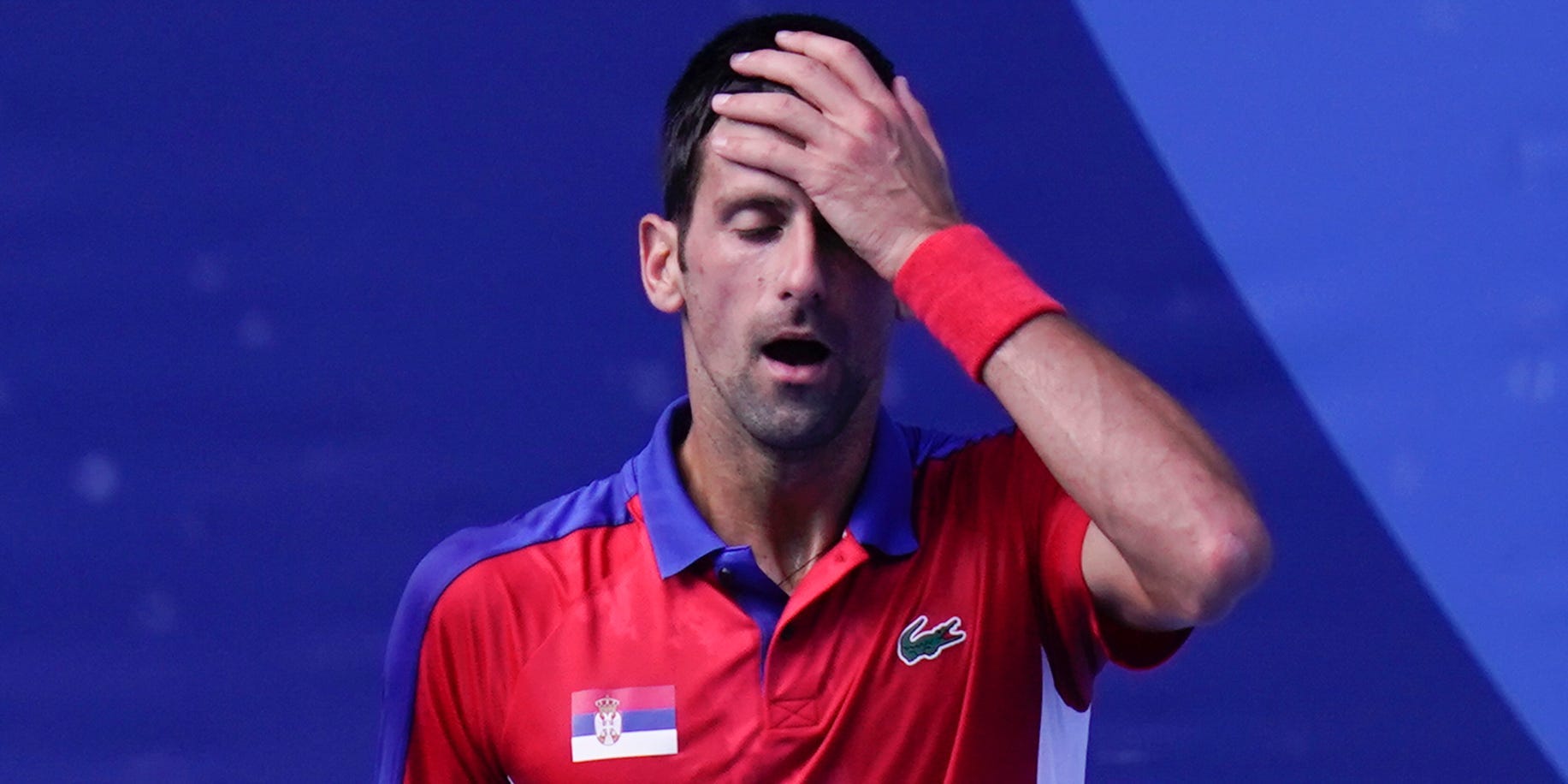 Novak Djokovic puts his hands to his head at the Tokyo Olympics.