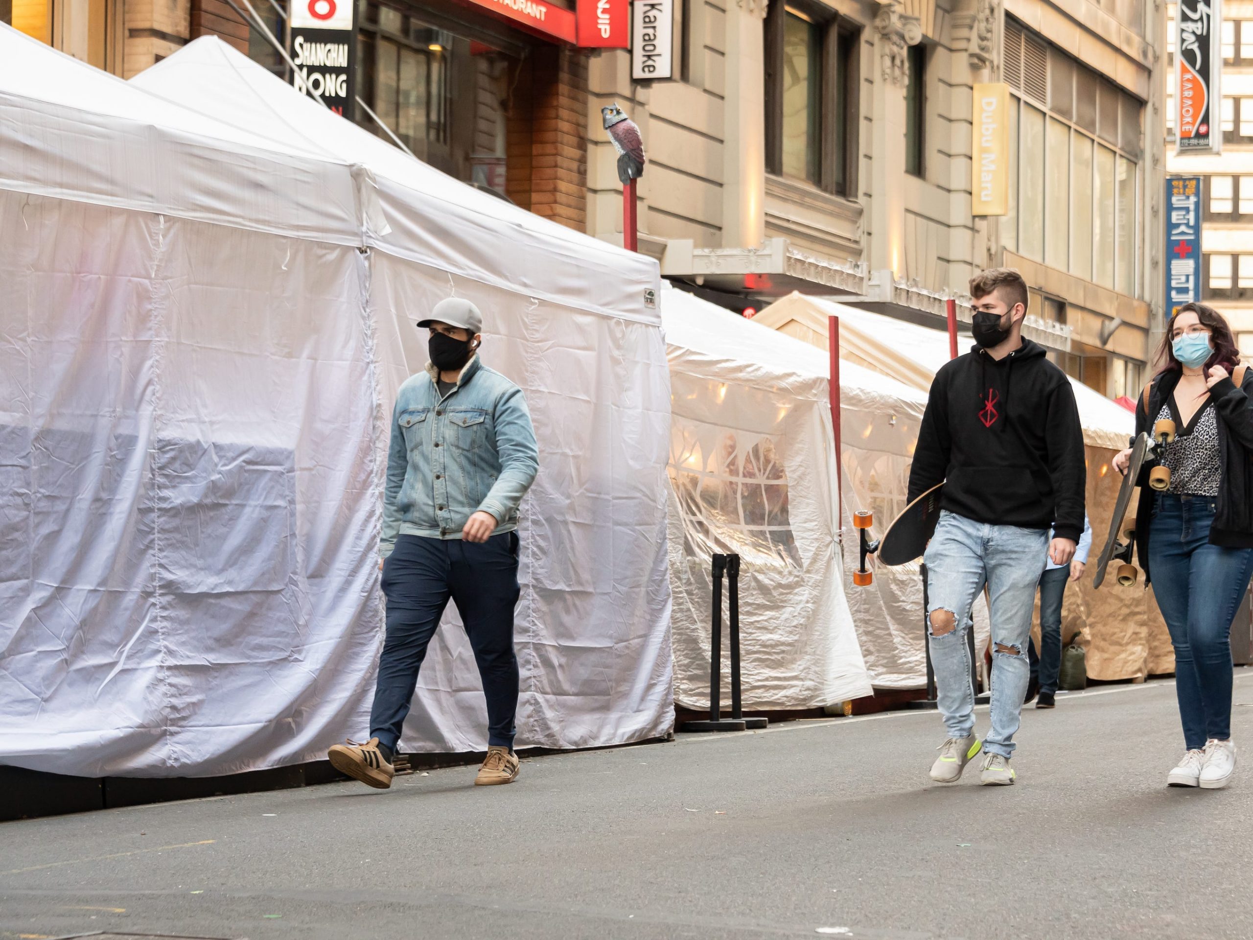 Photos of people walking by covered outdoor dining tents in New York City.