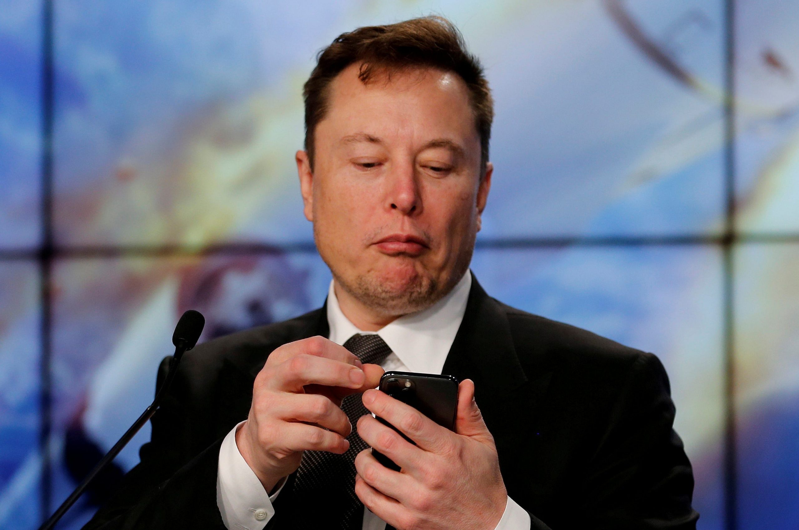 Elon Musk looking at his iPhone