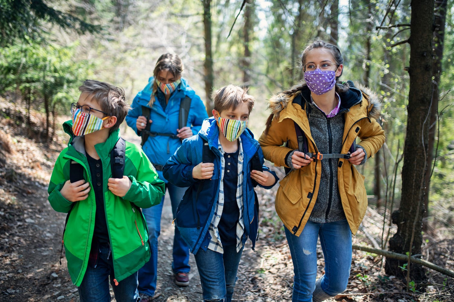 Family enjoying hiking in forest during the COVID-19 pandemic - stock photo
