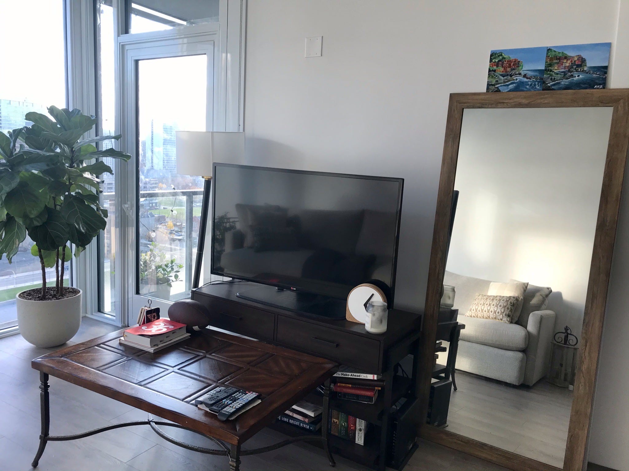 The writer's TV on top of a black TV stand and next to a mirror.