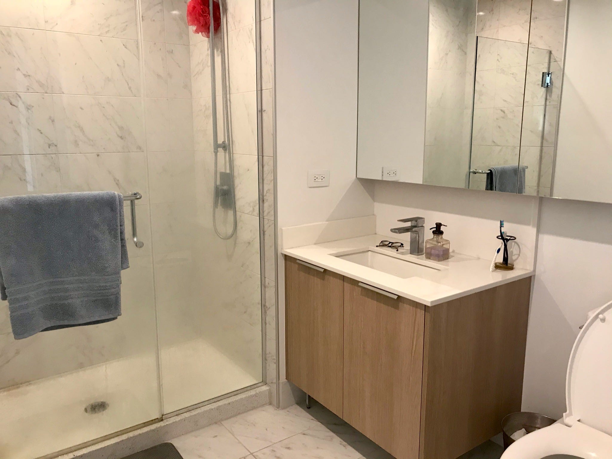 The writer's bathroom with a glass-walled shower and beige vanity.