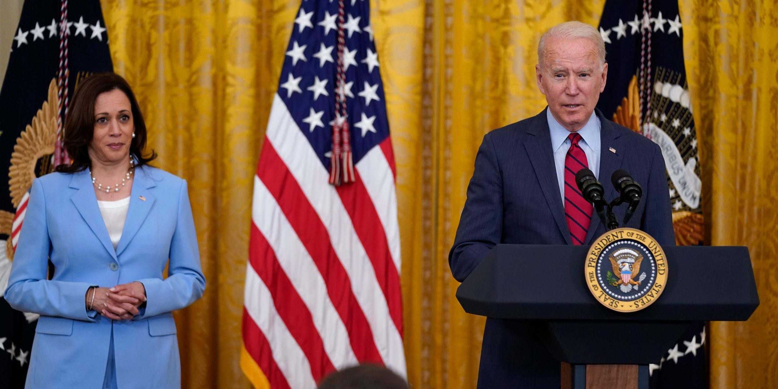 Joe Biden stands at a podium while Kamala Harris stands behind him.