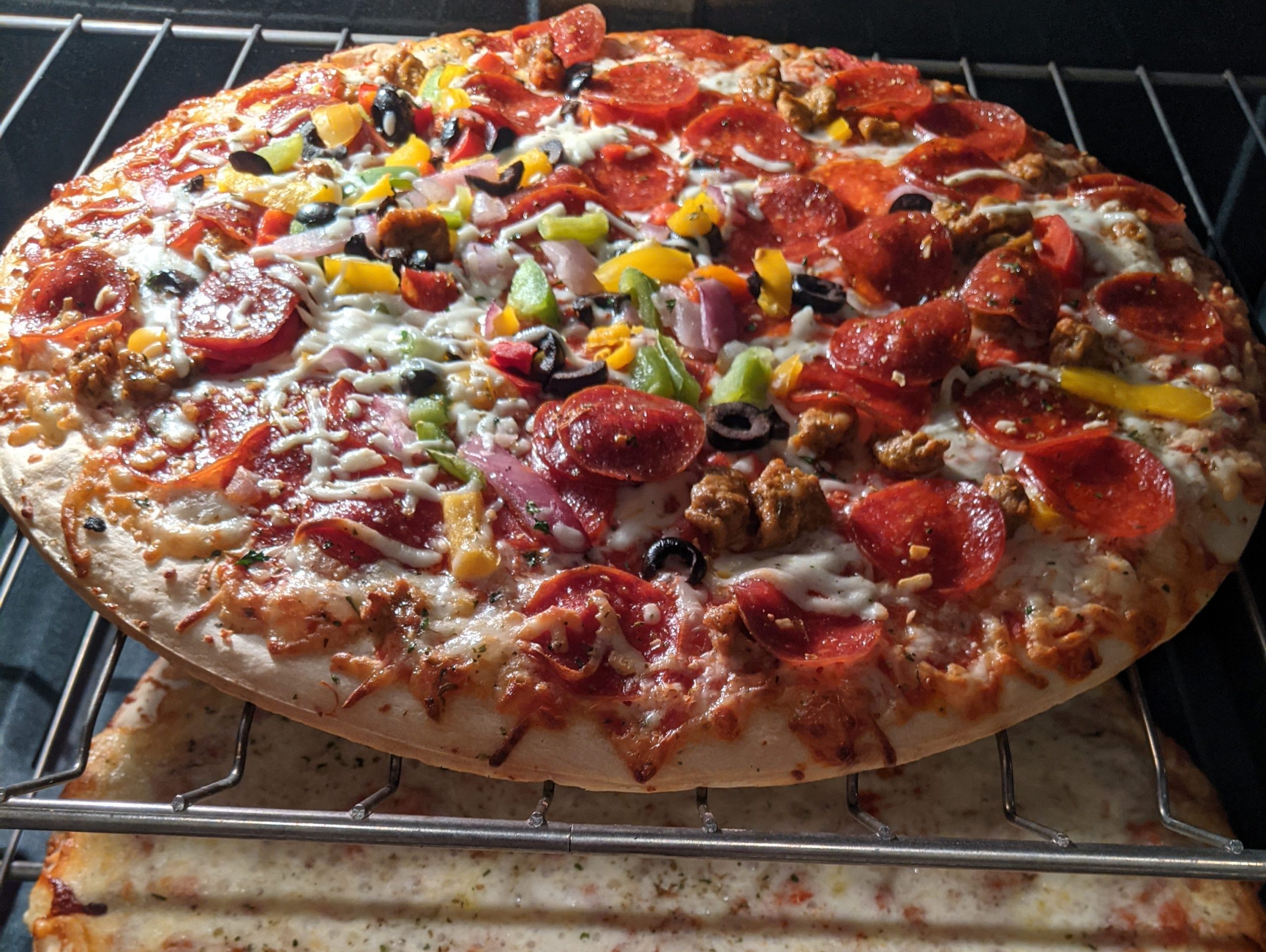 Two pizzas - one loaded with veggies and one with cheese - sitting on oven racks