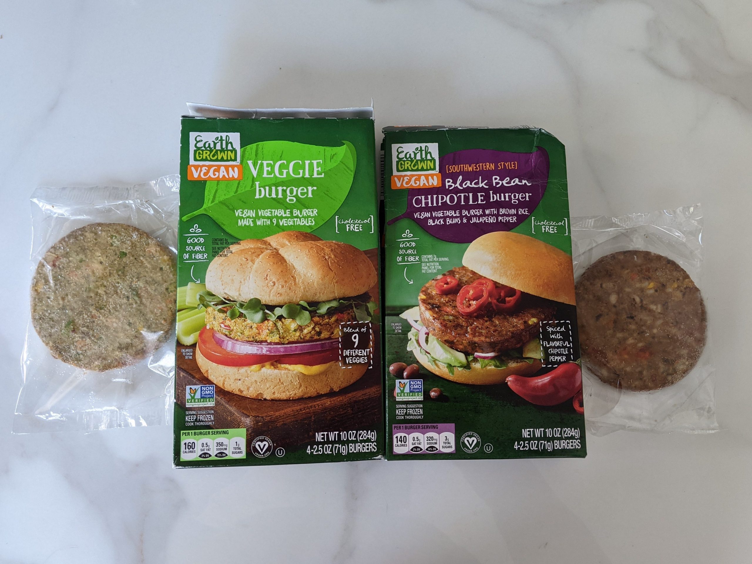 Aldi's veggie burgers in clear plastic and the two original green boxes on a white countertop