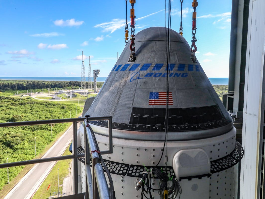 boeing starliner space capsule lowered on cables to rocket