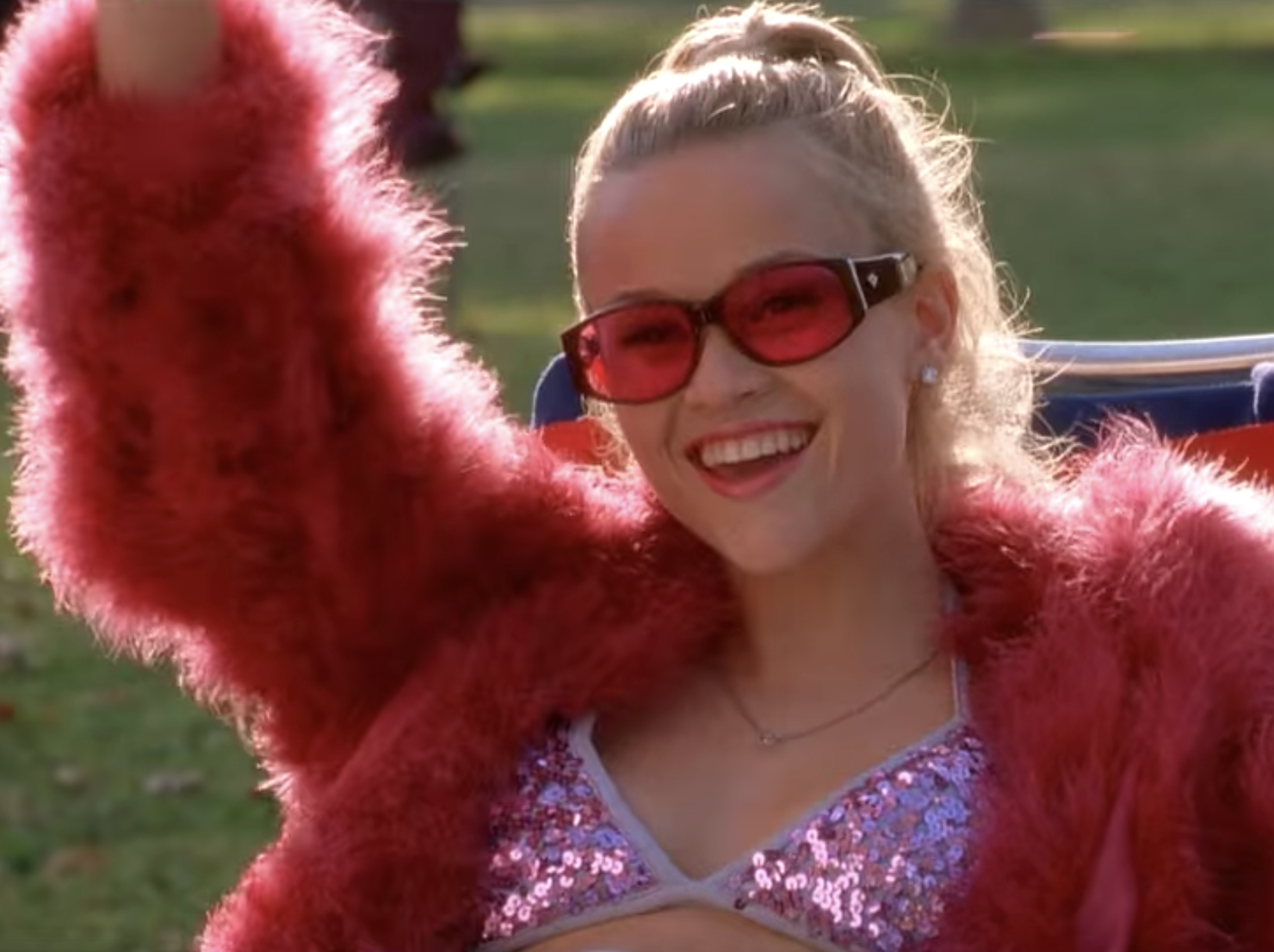 Reese Witherspoon wearing a pink outfit and holding a drink in "Legally Blonde."