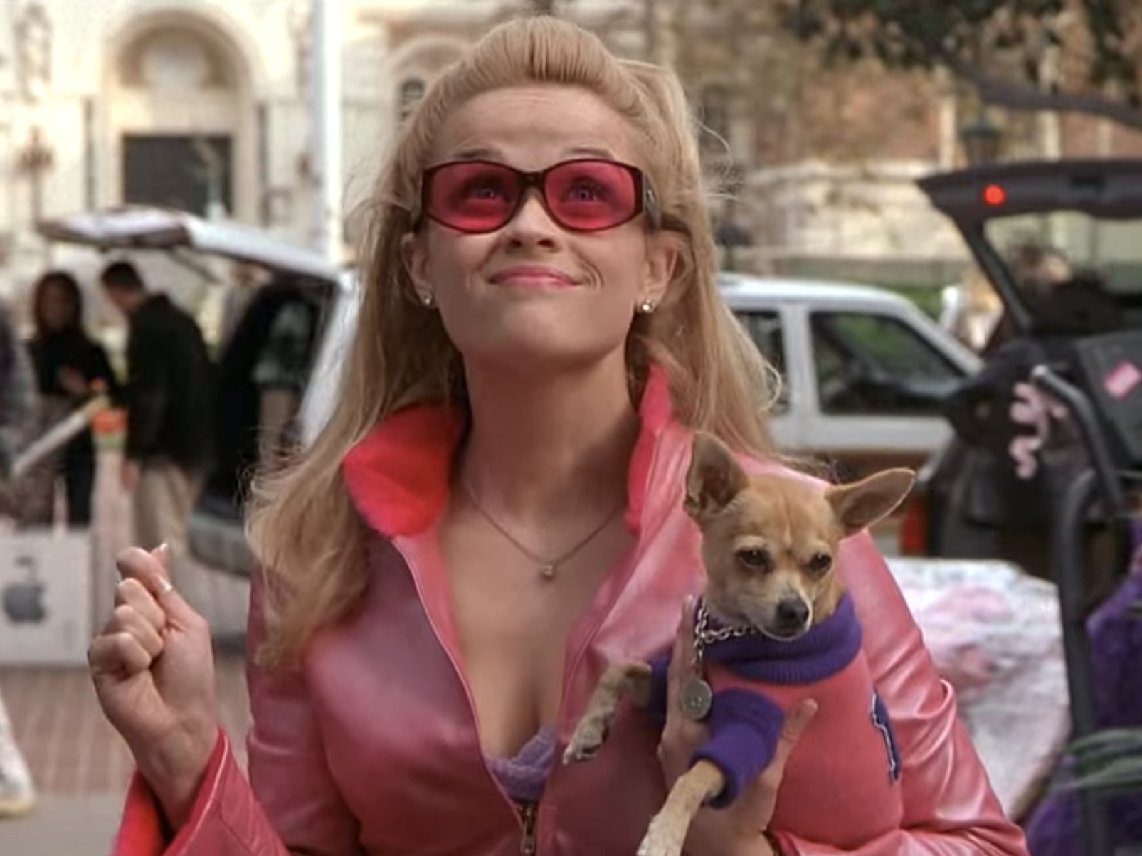 Reese Witherspoon wearing a pink outfit and holding a dog in "Legally Blonde."