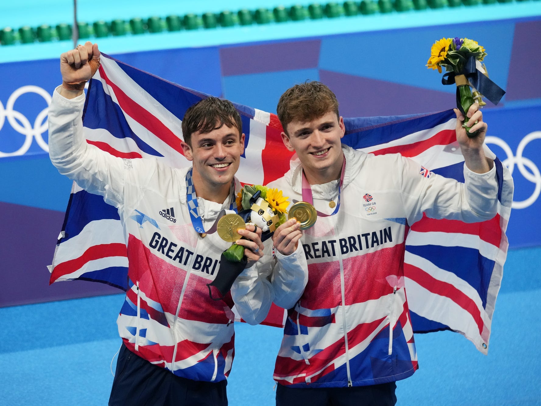 Tom Daley (left) and Matty Lee (right) hold up their gold medals on the podium at the 2020 Tokyo Olympics.