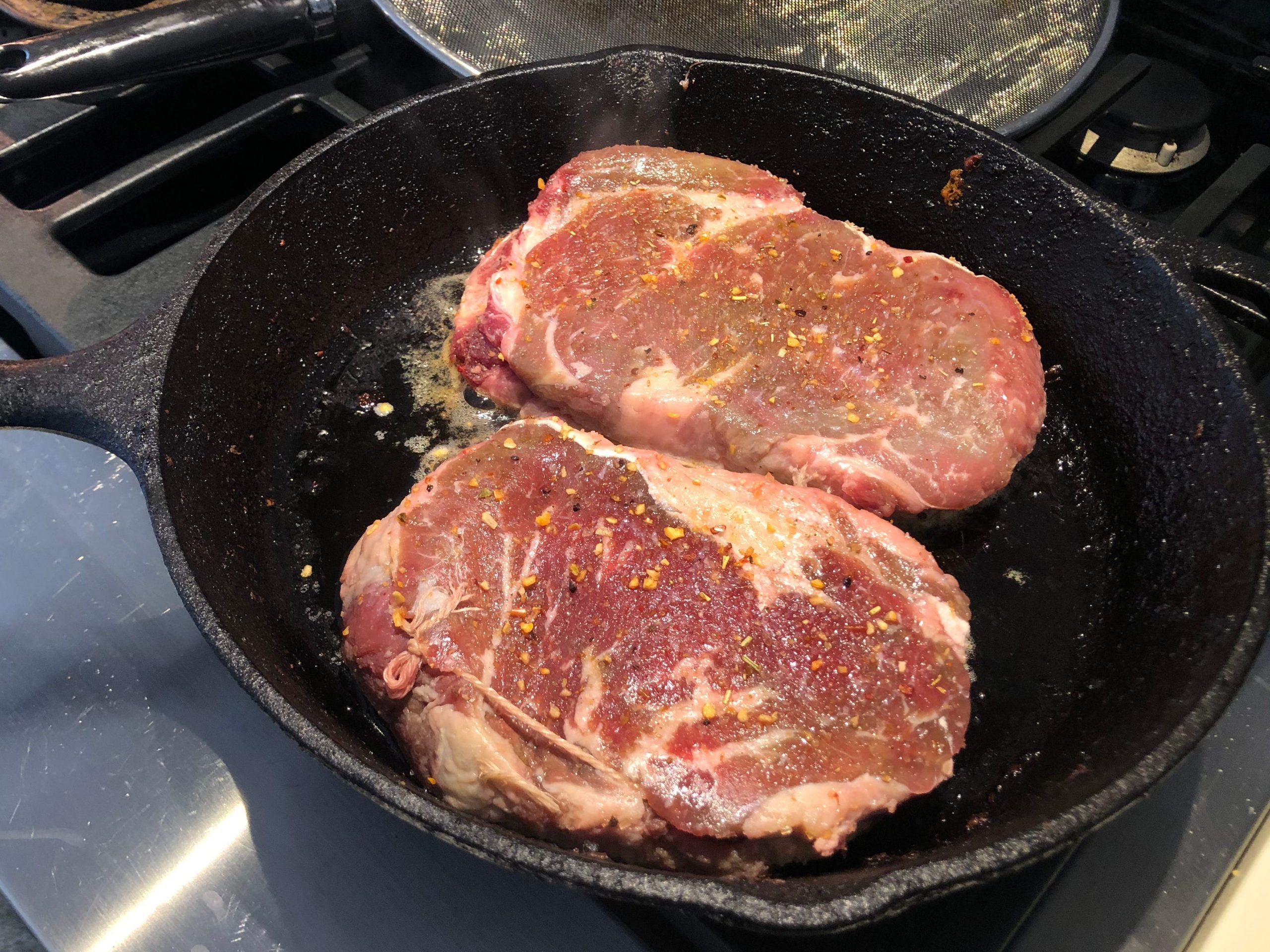 Two steaks in a cast-iron skillet.