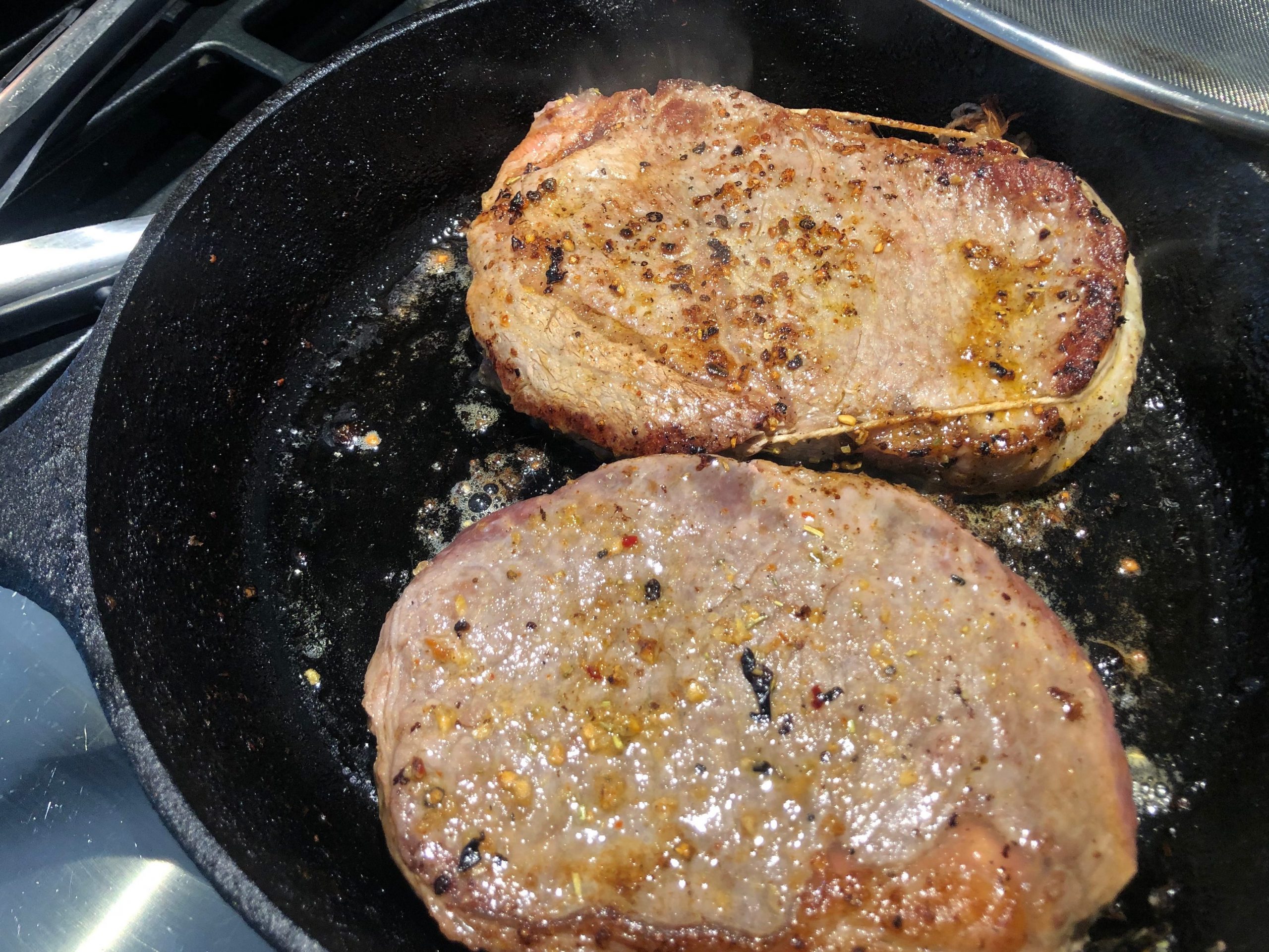 Two steaks in a cast-iron skillet.