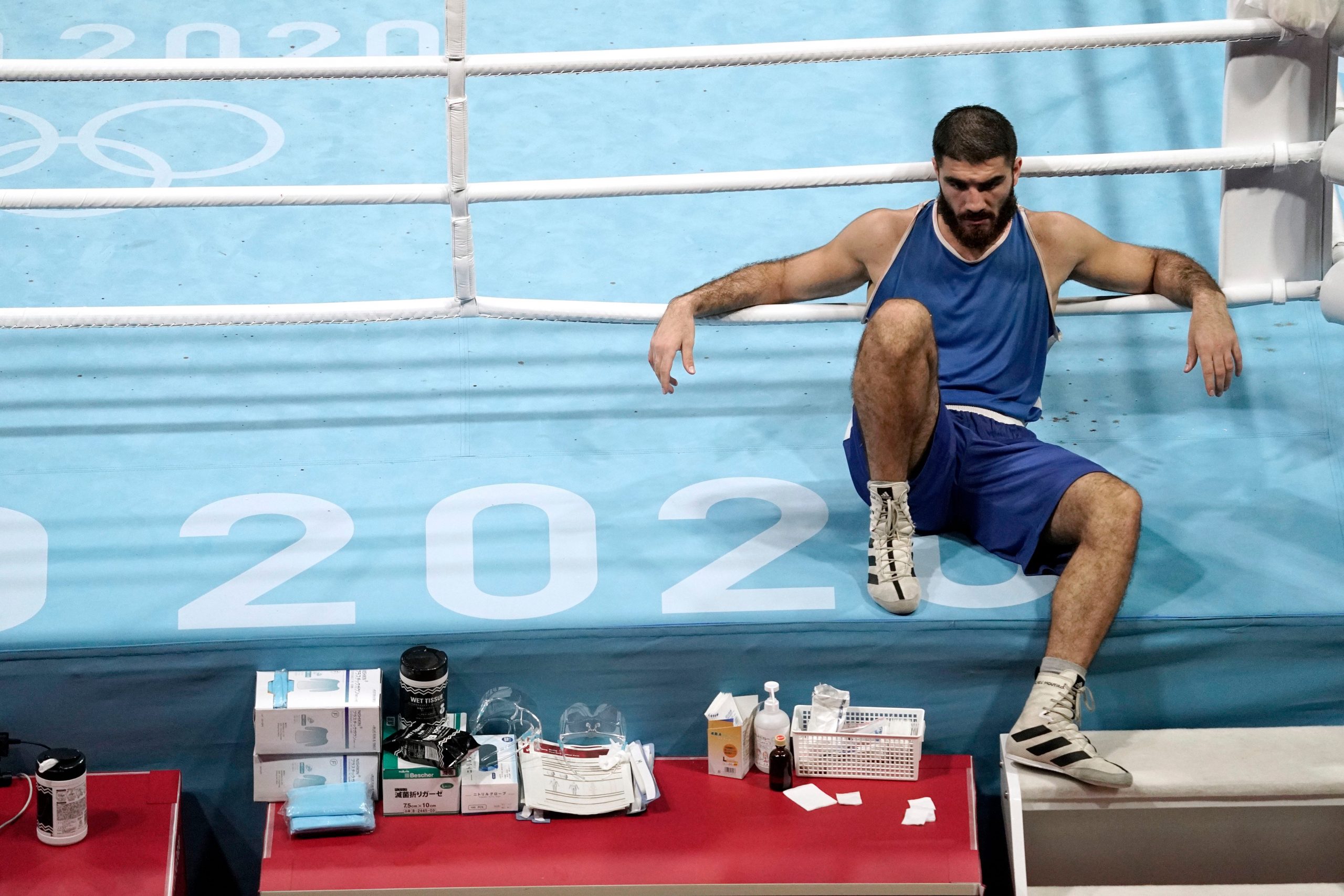 Mourad Aliev sits on the ring apron, with his arms on the ropes.