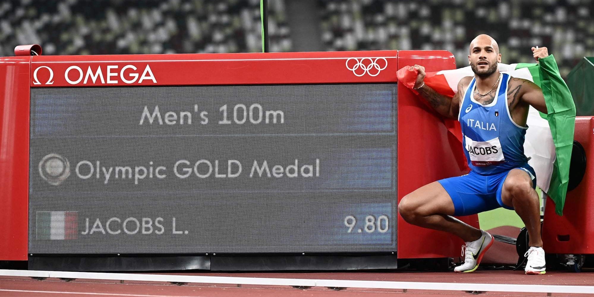 Italy's Lamont Marcell Jacobs poses next to the scoreboard displaying his gold medal result after winning the men's 100 meter final during the Tokyo 2020 Olympic Games.