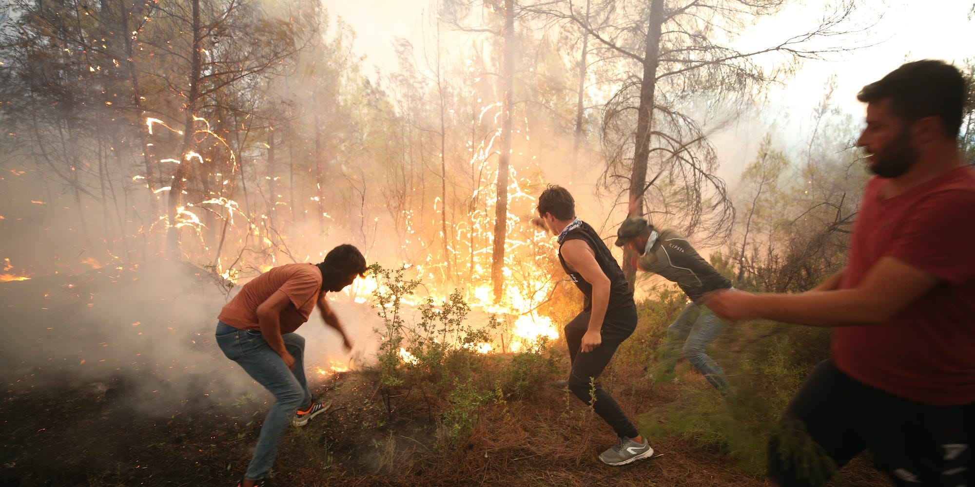 Three men help with the fight against forest fires broke out in Antalya, Turkey