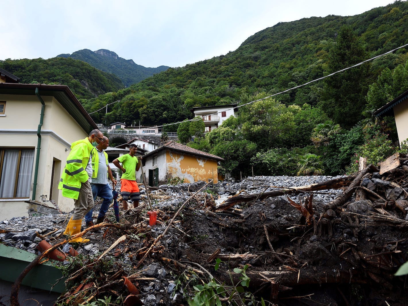 People stand in an area where a landslide has destroyed several houses after heavy rain caused flooding in towns surrounding Lake Como in northern Italy, in Laglio, Italy.