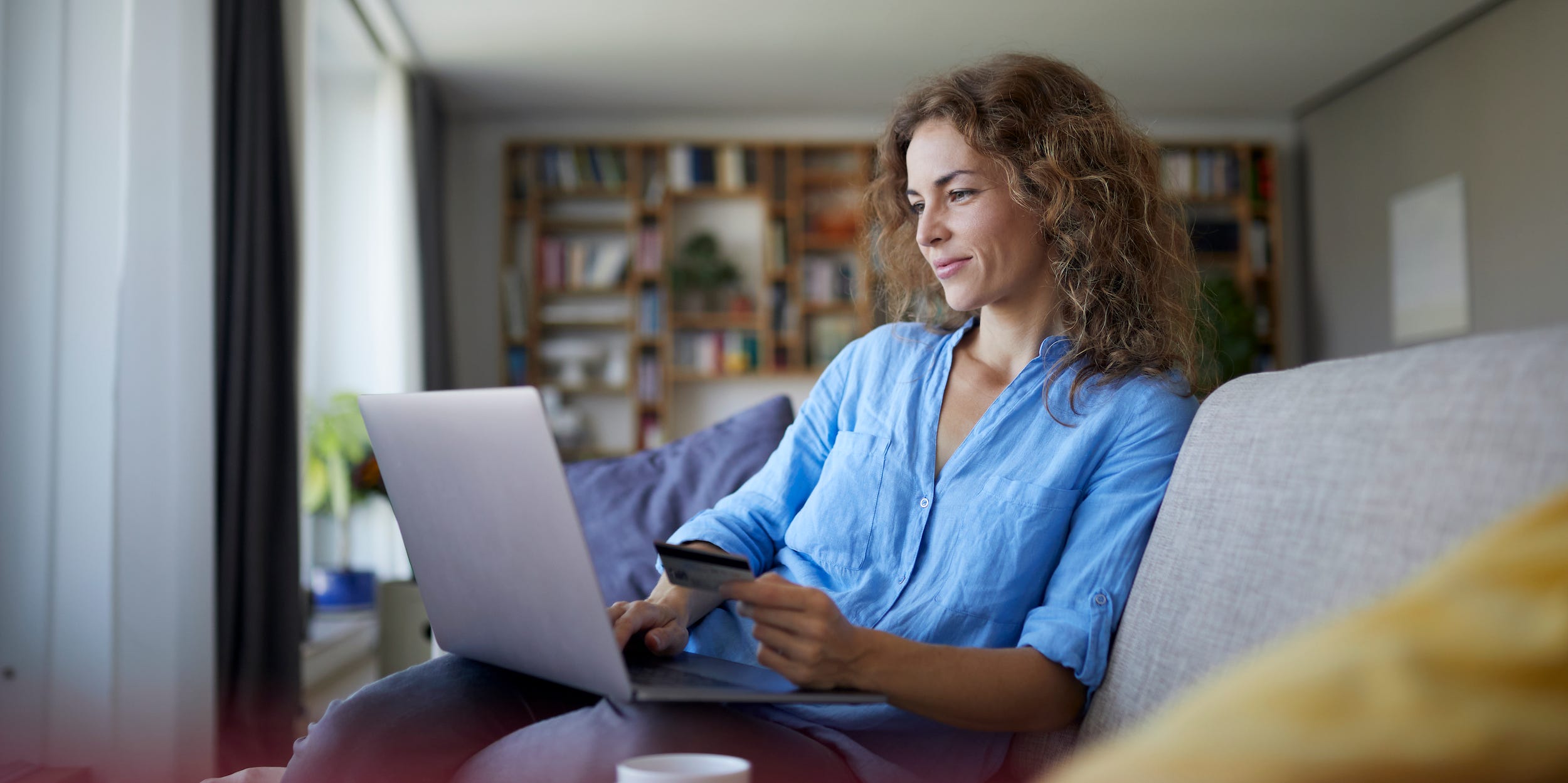 Woman at home using laptop online shopping with credit card in hand