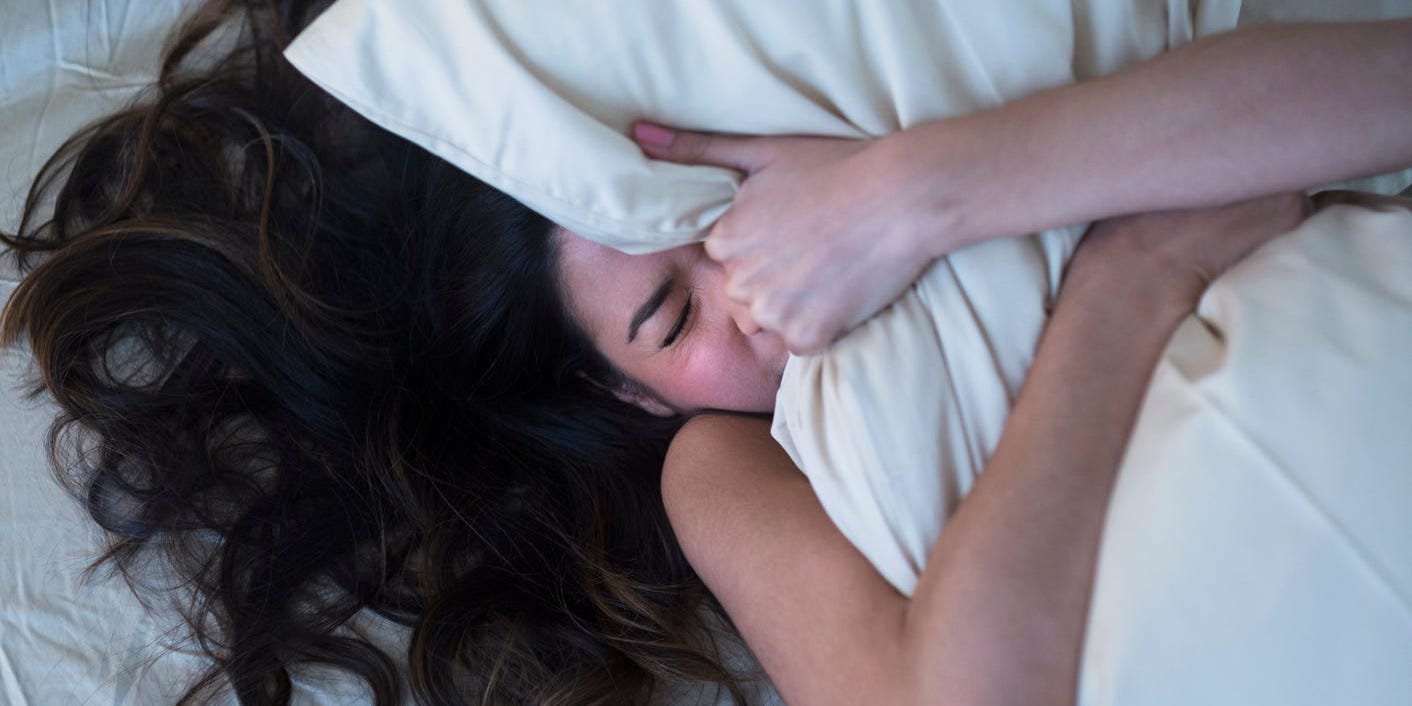 Woman having a nightmare hugging pillow trying to sleep