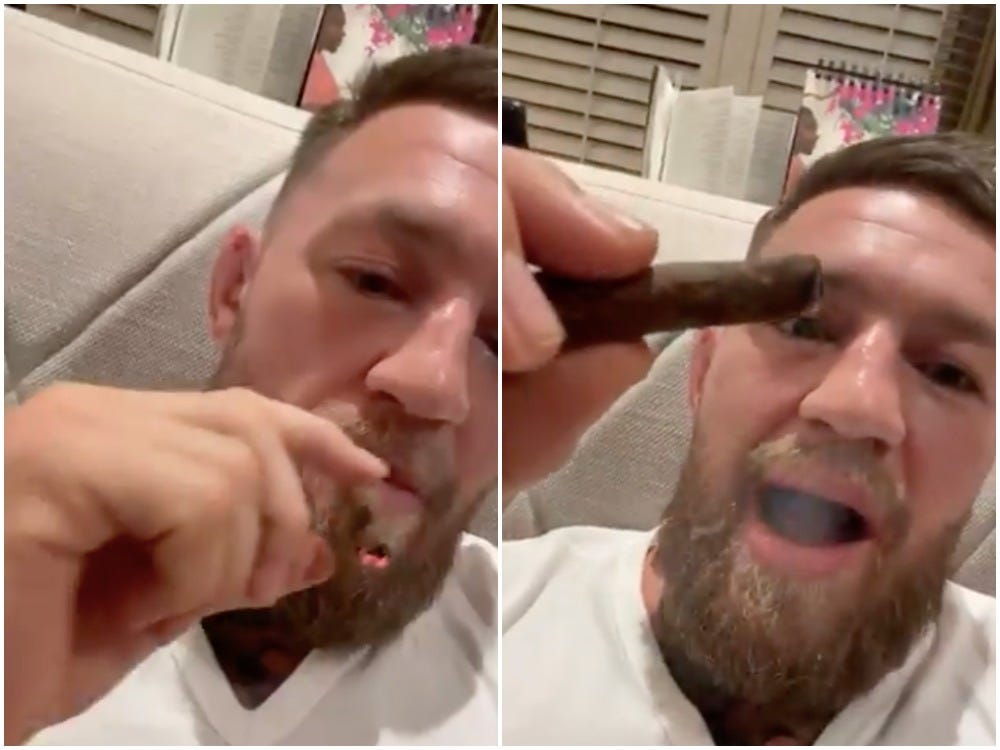 Conor McGregor laughs while smoking what appears to be a blunt.