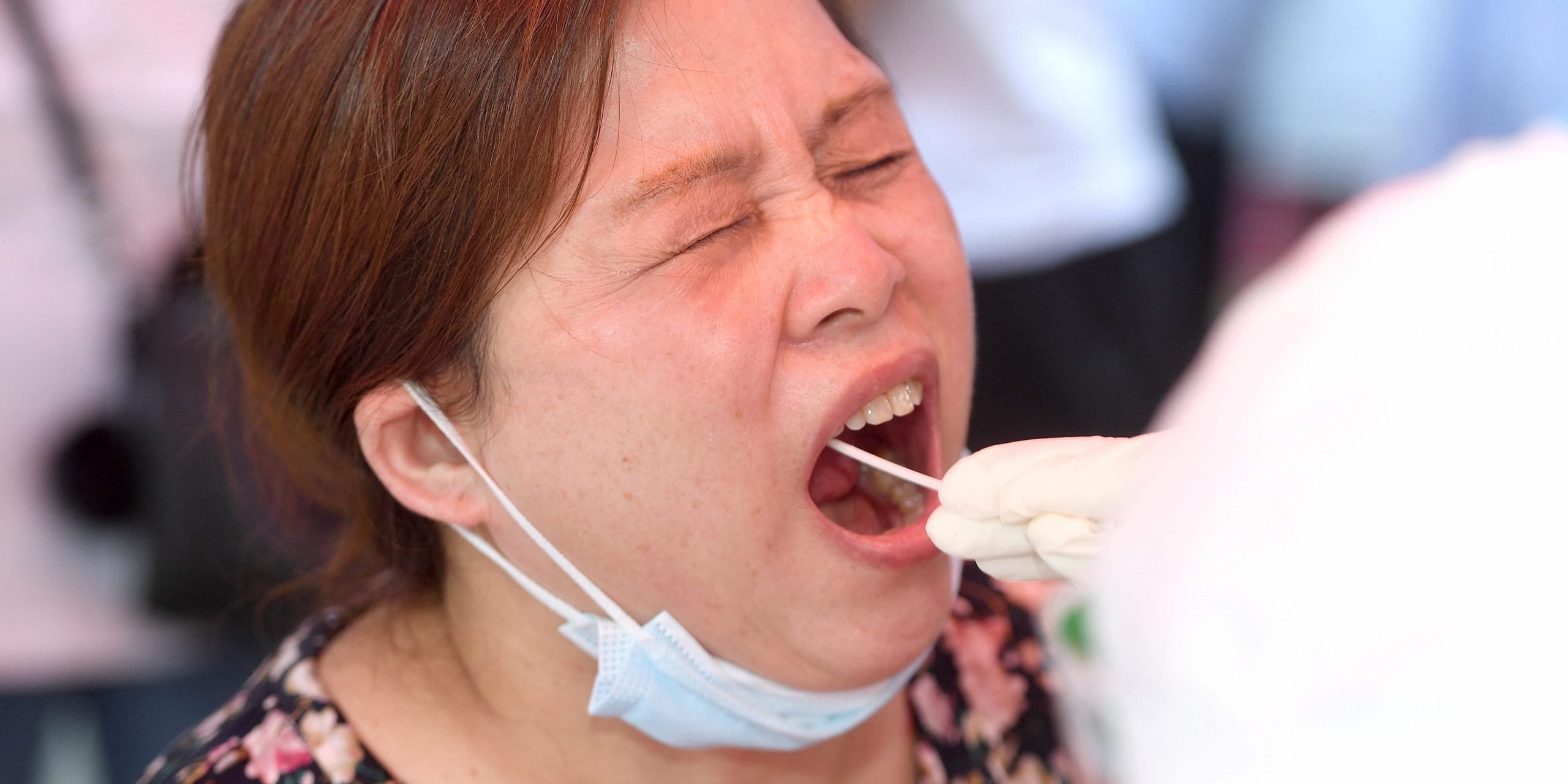 A woman opens her mouth and closes her eyes as a swab is put in her mouth