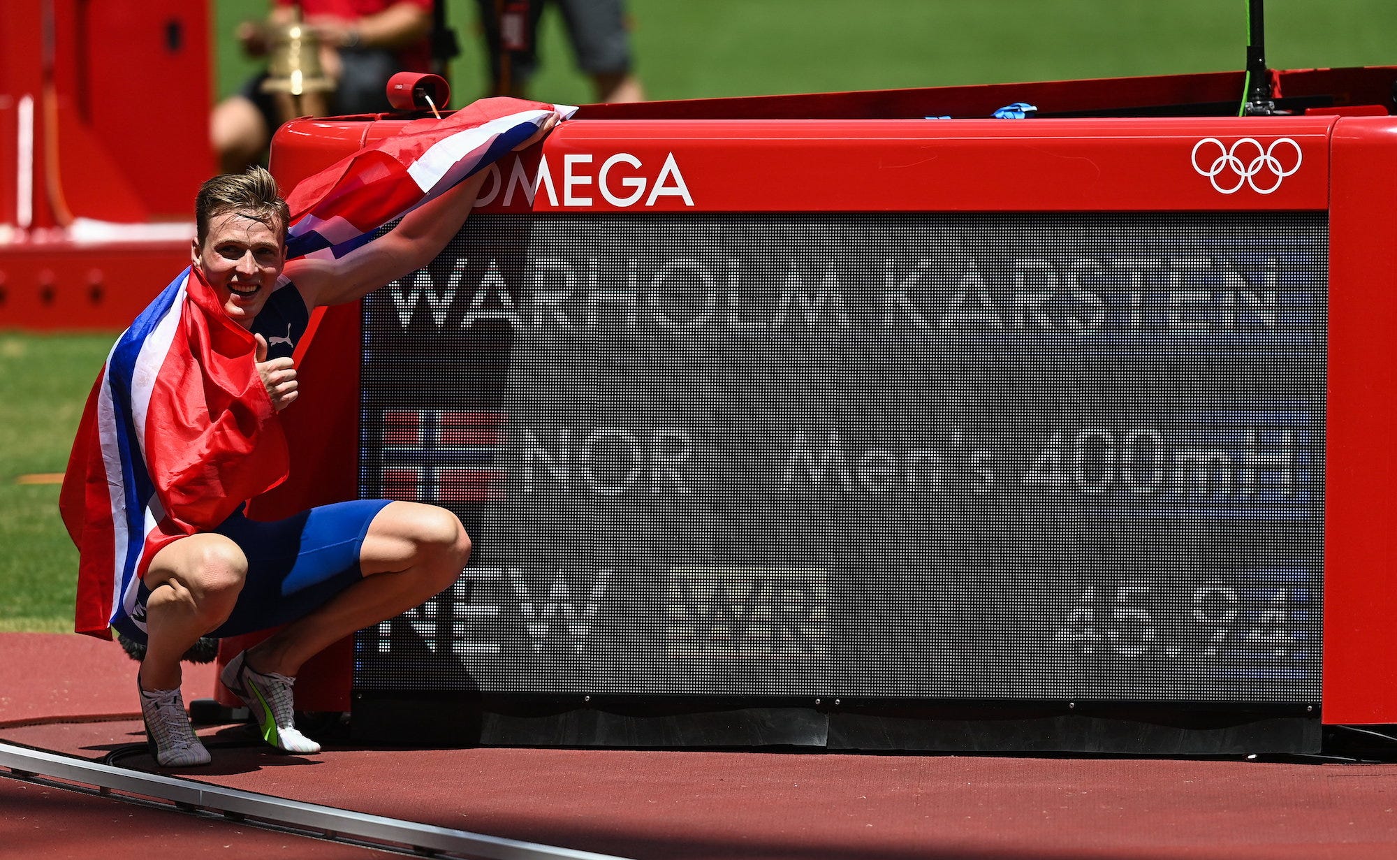 Warholm Karsten poses alongside a digital board which displays his world record finish.