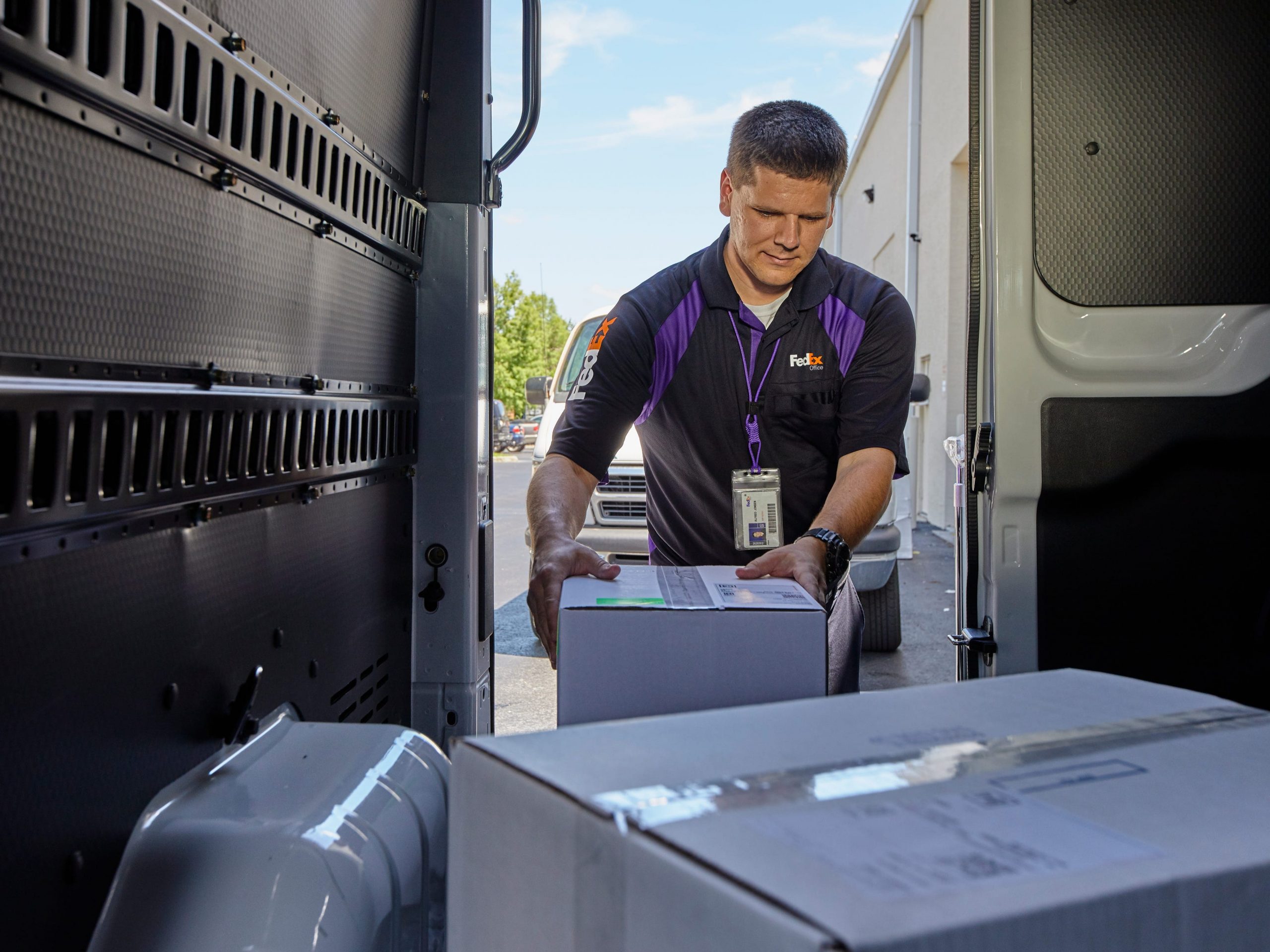 A FedEx delivery person takes a box out of a truck.