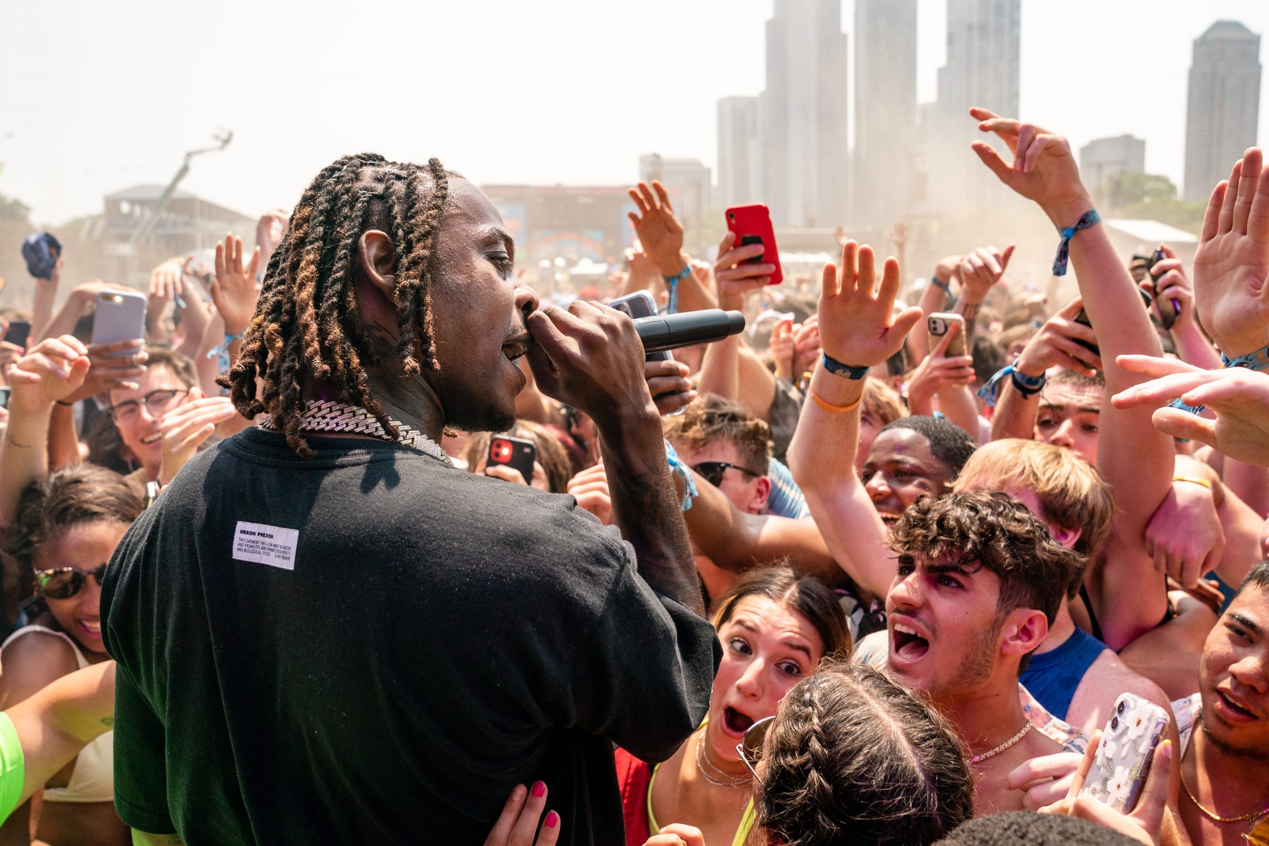 Flipp Dinero faces a crowd of people with a microphone in his hand.