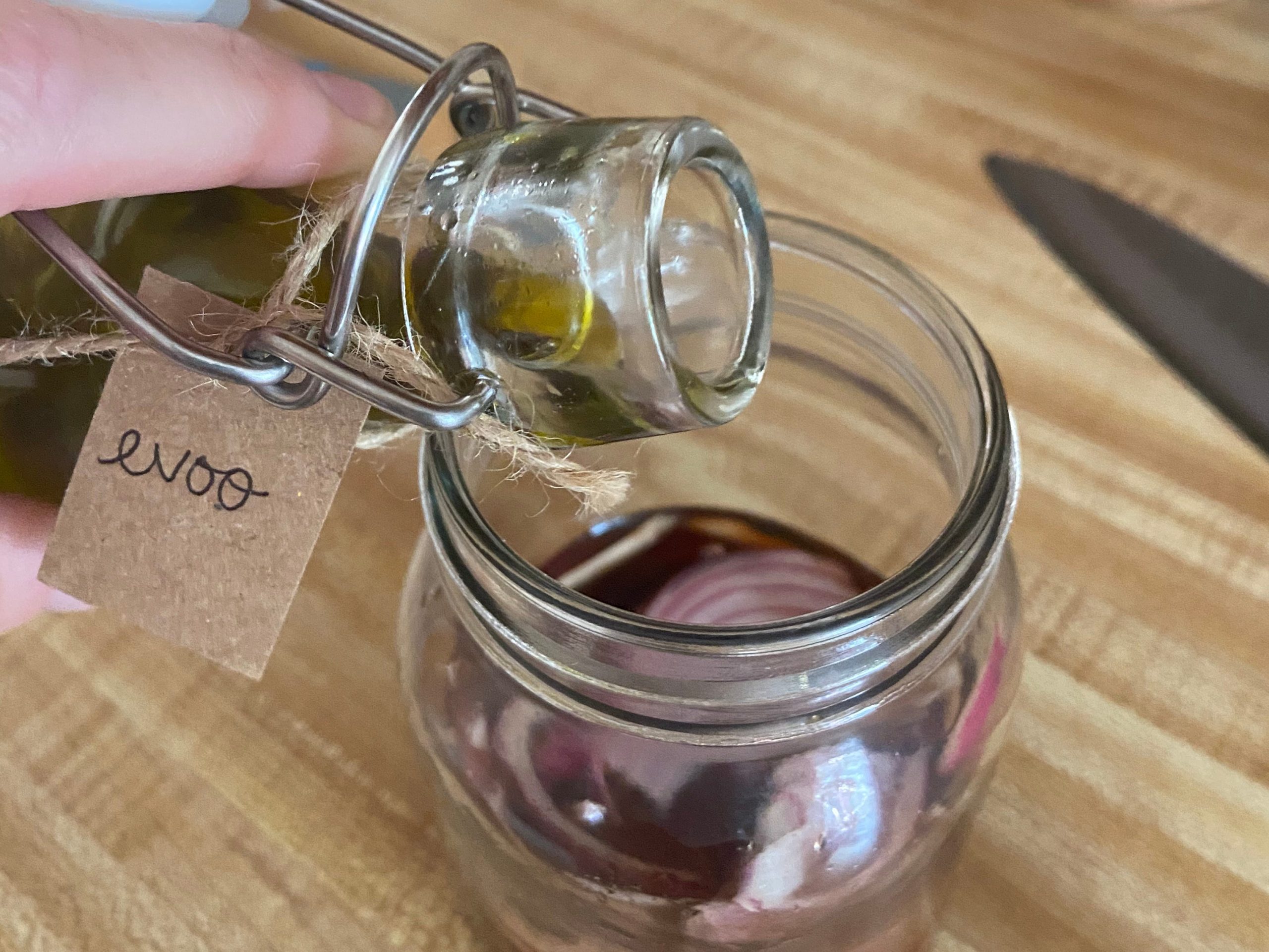 Adding extra virgin olive oil to jar of vinegar and onion