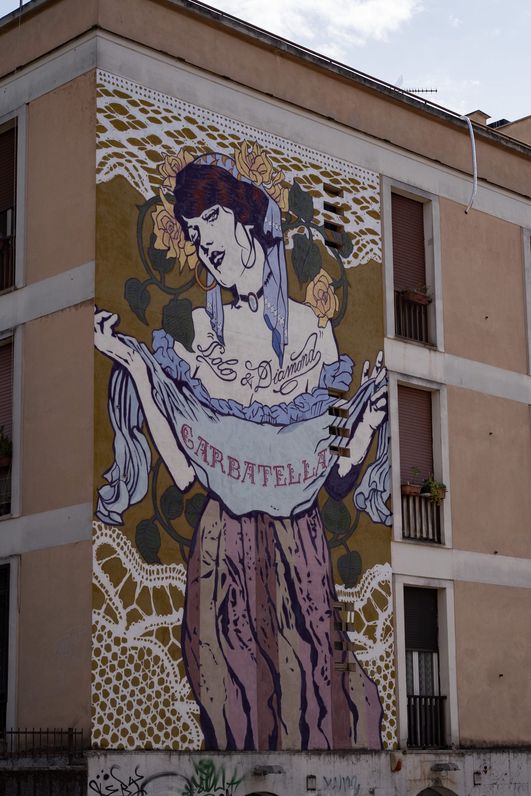 A mural of a woman holding a shawl covers the side of a building.