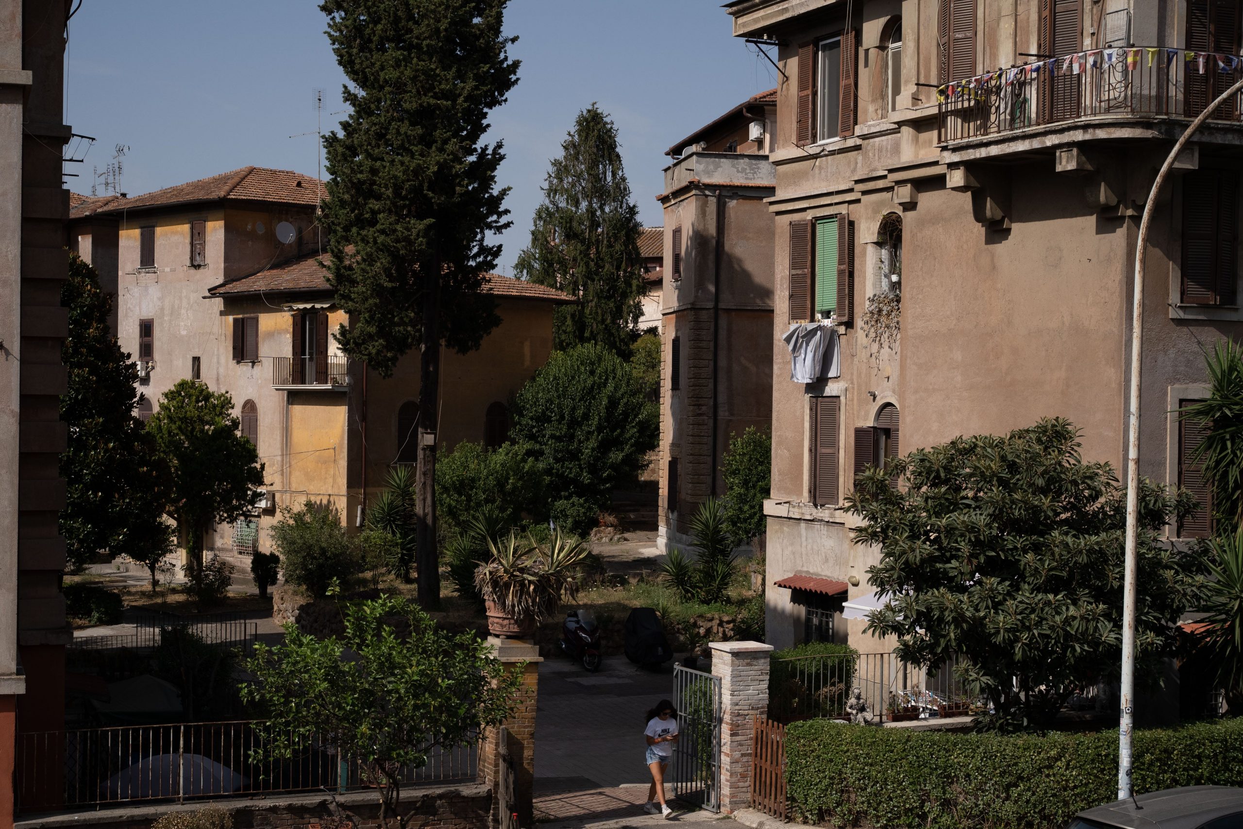 A gate leads to a green area surrounded by residential housing.