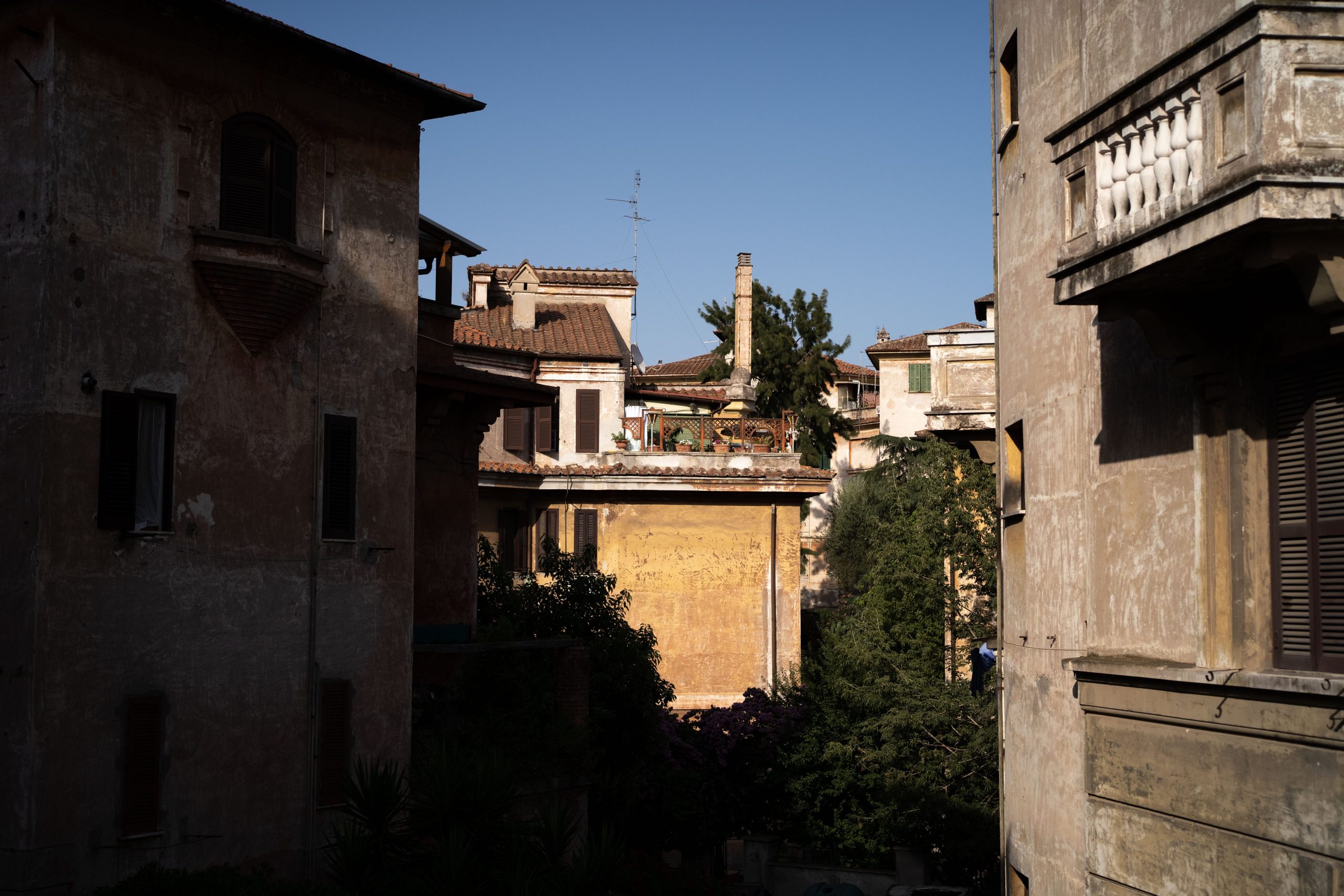 Apartment buildings are seen, partially covered in shadow.