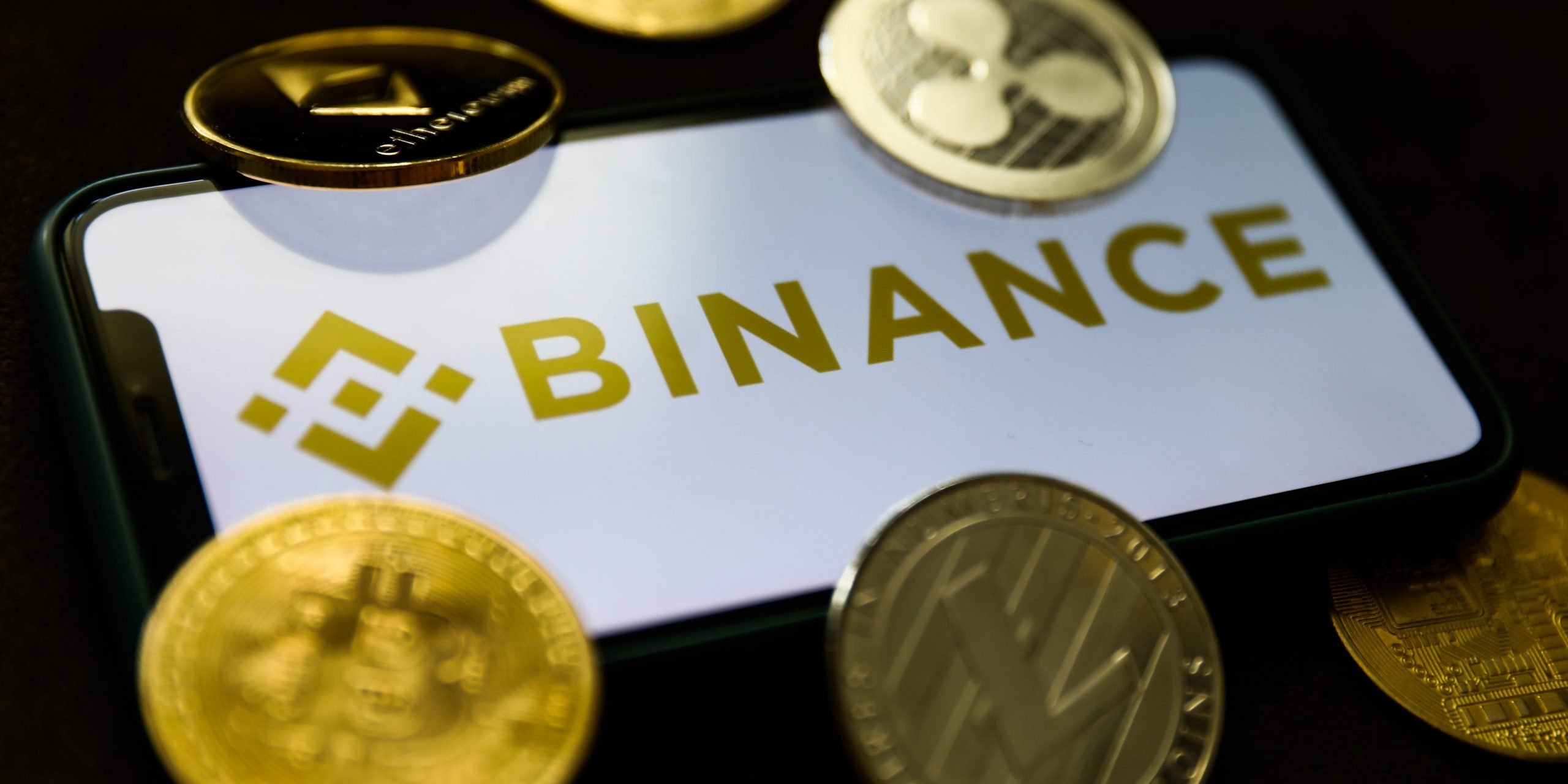 Binance logo displayed on a phone screen and representation of cryptocurrencies are seen in this illustration photo taken in Krakow, Poland on June 28, 2021