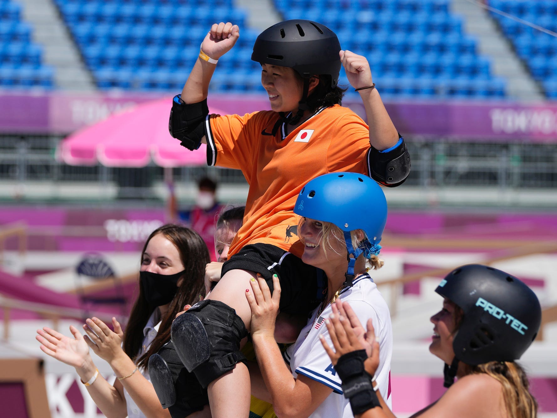 Misugu Okamoto raises her hands while being carried on the shoulders of other skaters at the Tokyo Olympics