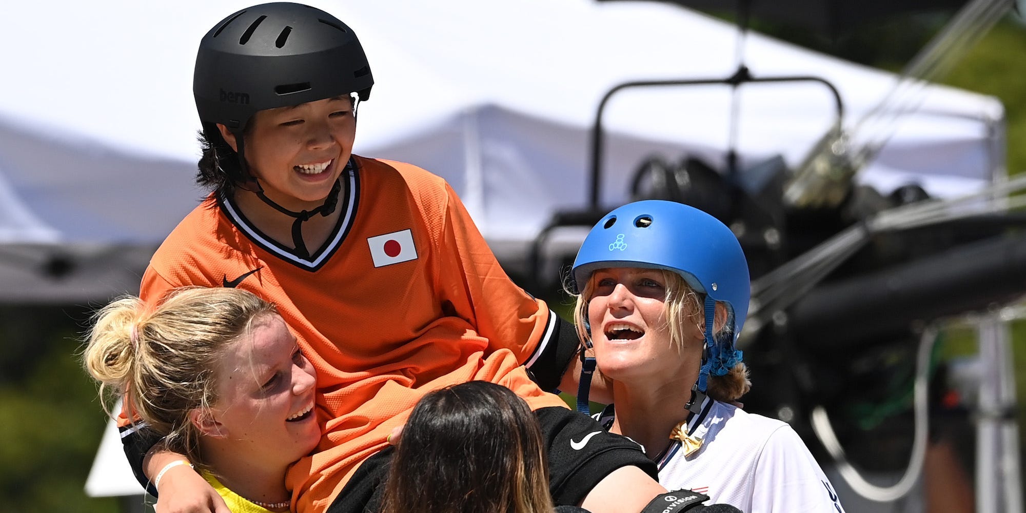 Olympic skateboarders carry Misugu Okamoto on their shoulders.